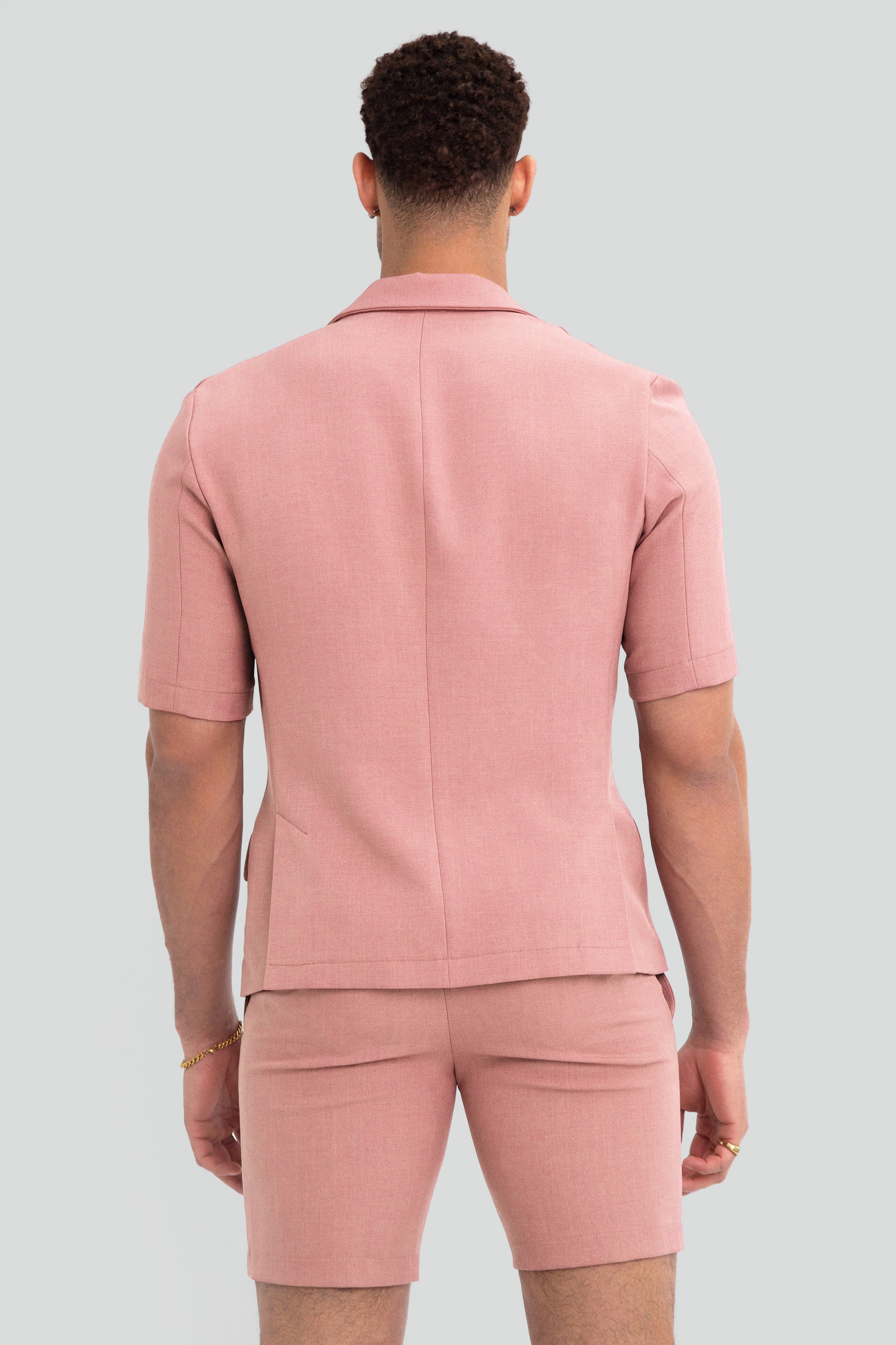Man wearing a light dusty pink short suit on a plain background