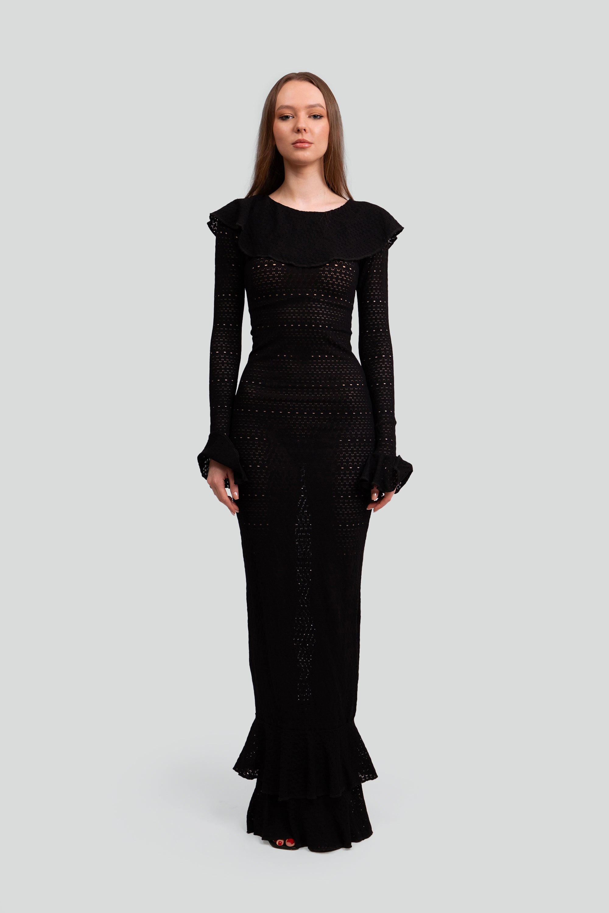 Woman wearing a black dress with ruffled details on a white background