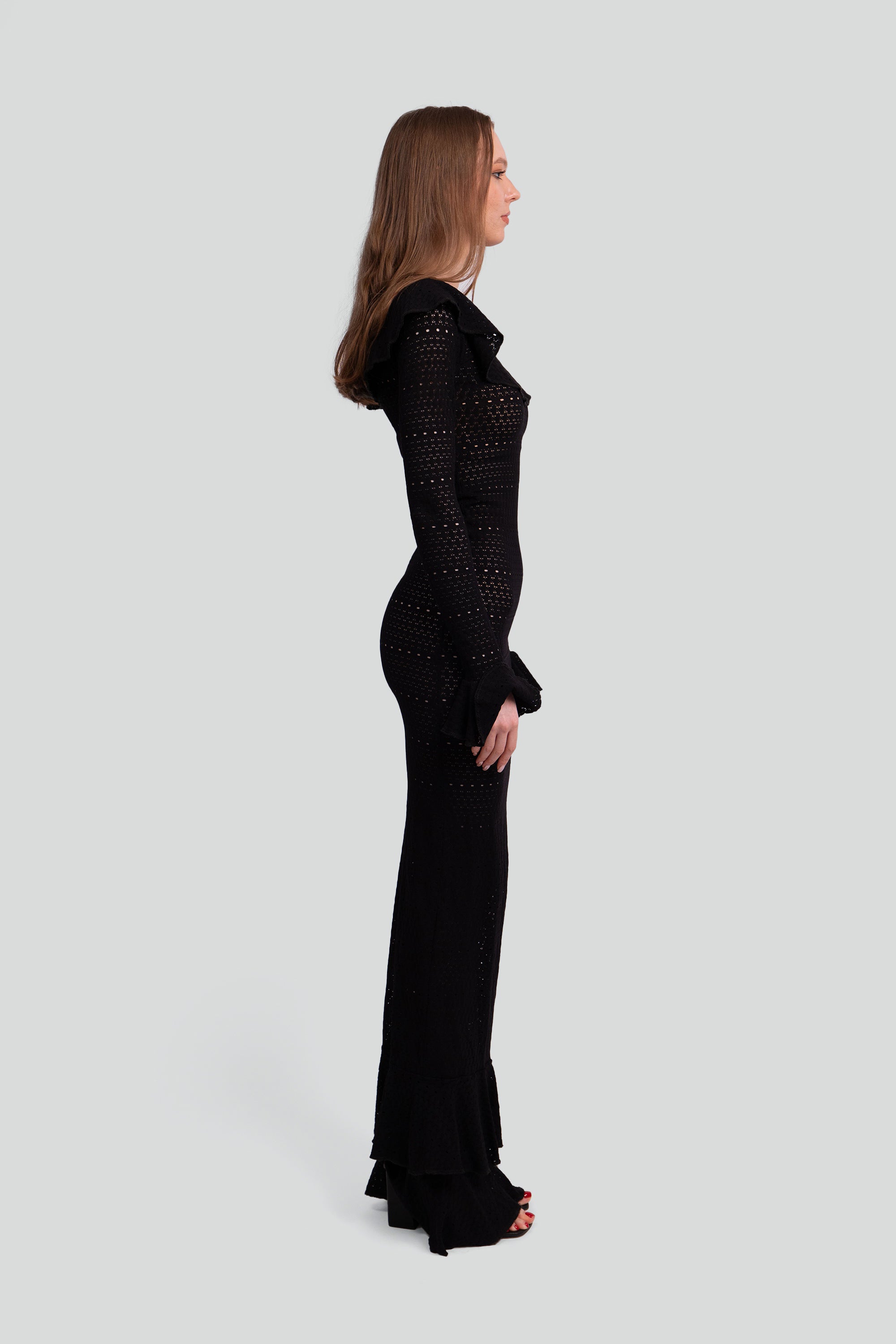 Woman wearing a black dress with ruffled details on a white background