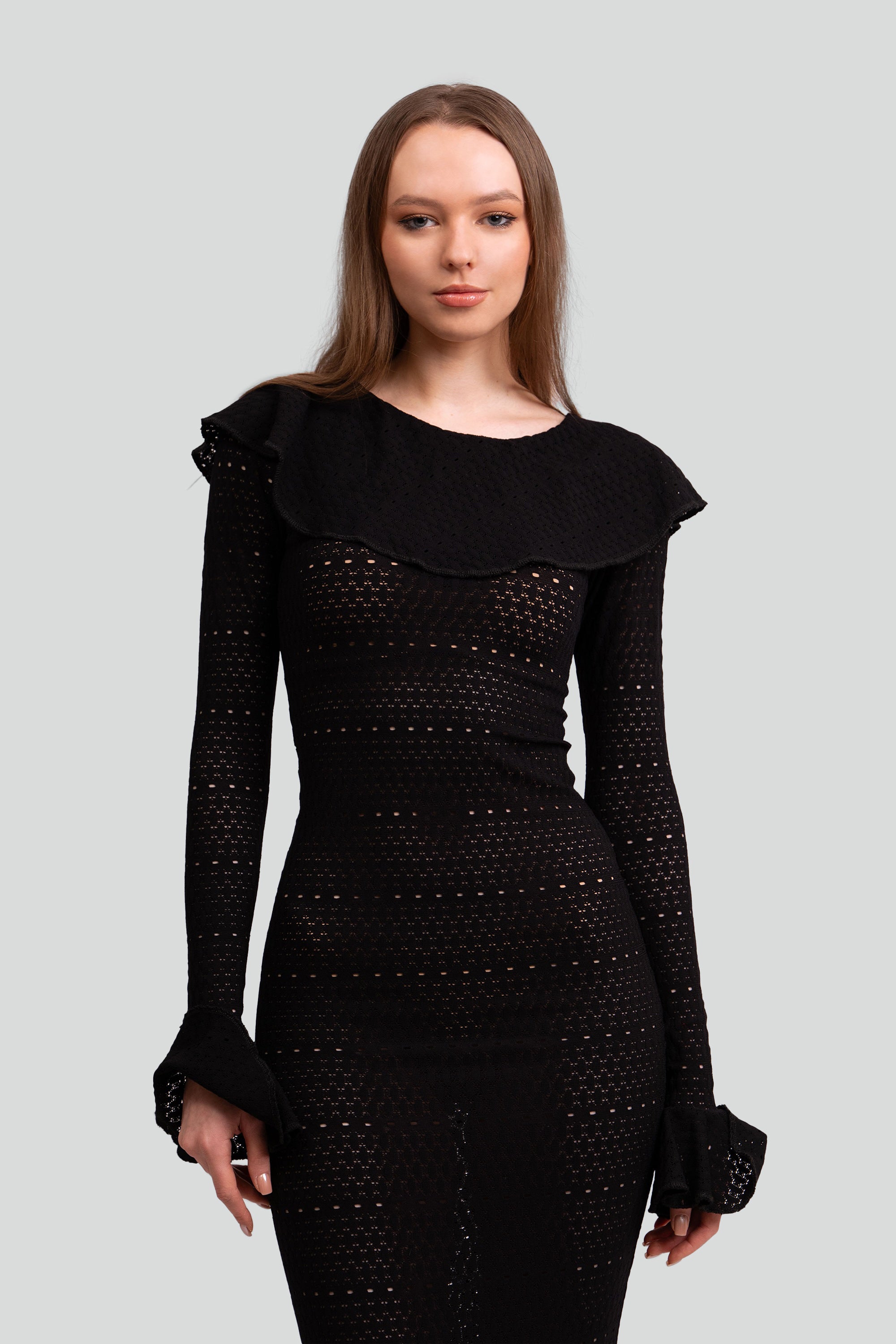 Close up of a woman wearing a black dress with intricate detailing on a white background