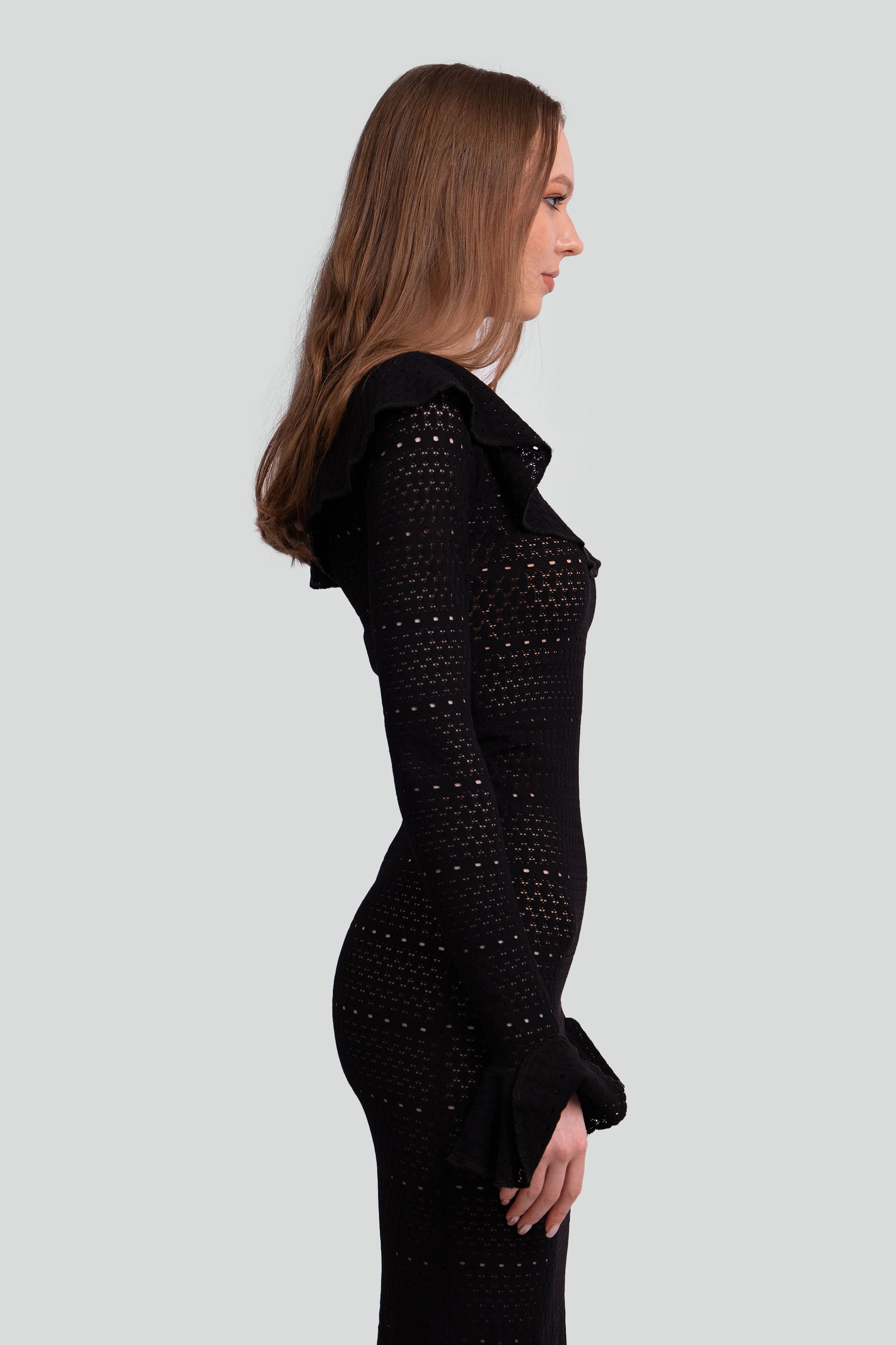 Woman wearing a black dress with intricate detailing on a white background