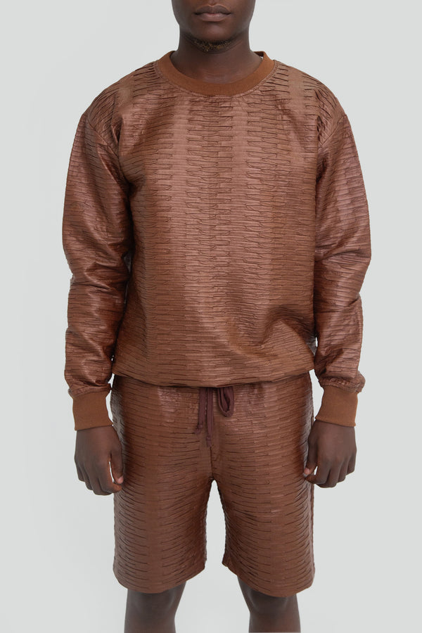 Man wearing a brown vegan leather shorts set featuring an oversized long sleeve top and matching drawstring sweat shorts
