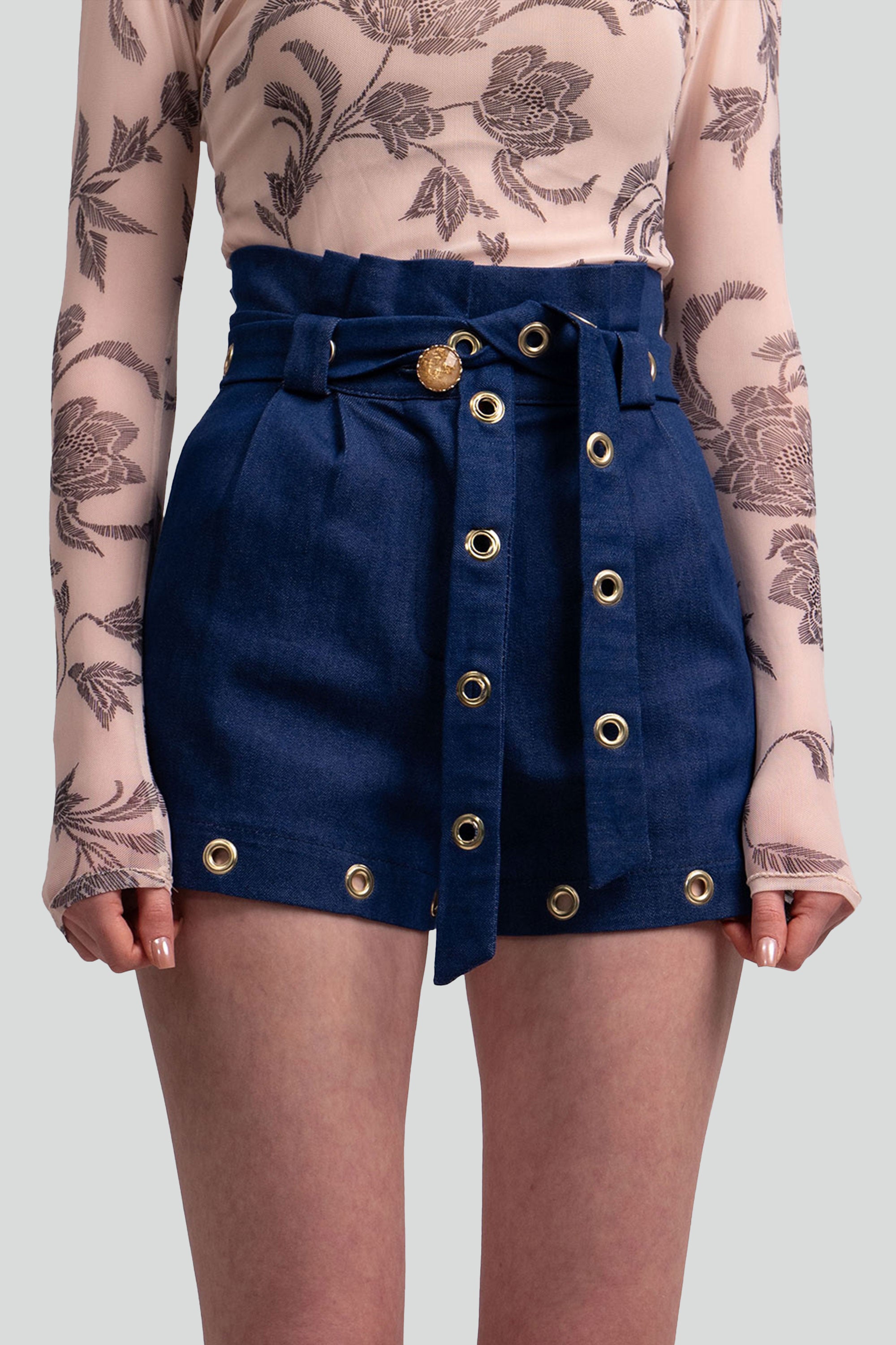 Navy blue shorts with gold grommets worn by a person on a white background