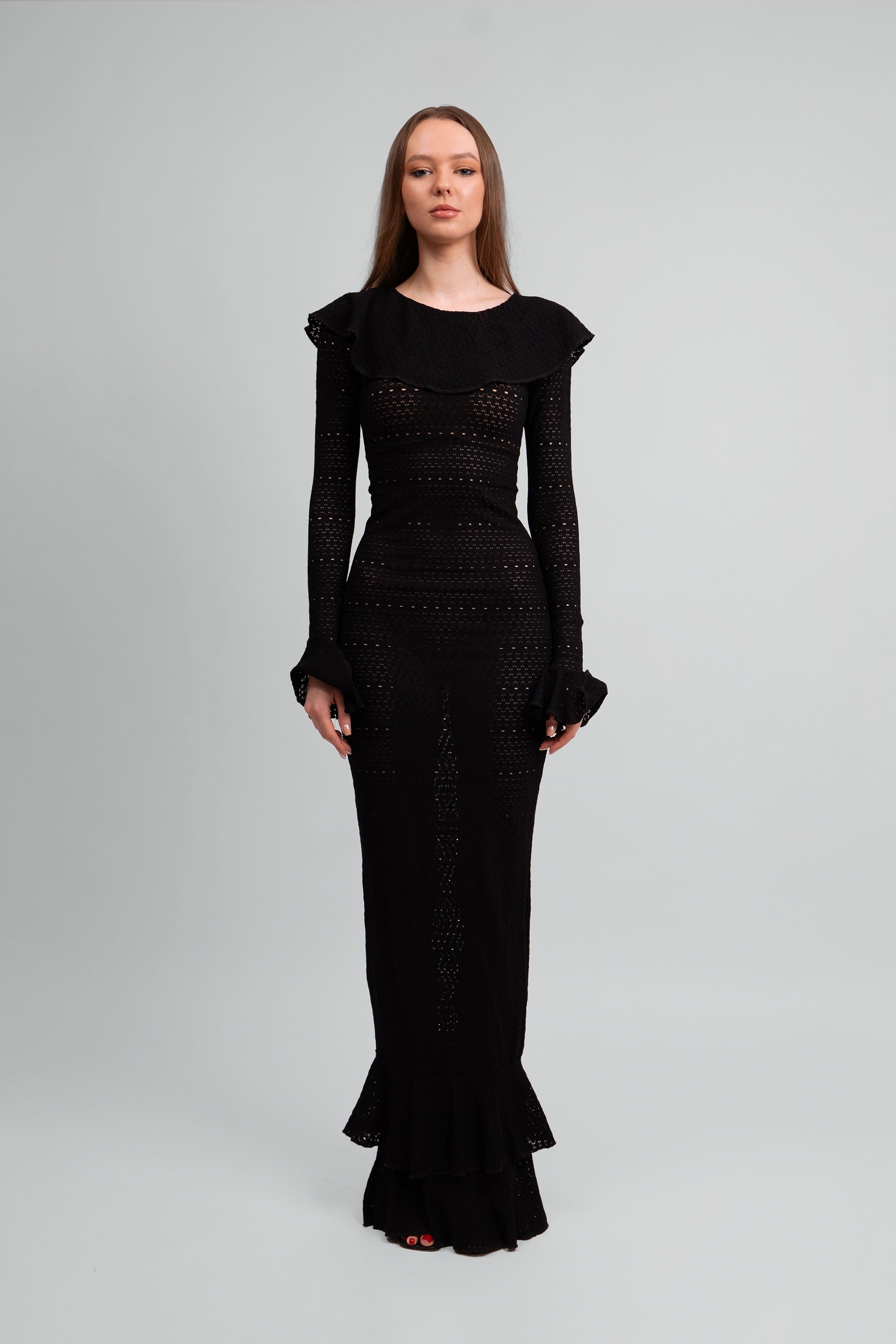 Woman wearing a black dress with ruffled details on a white background