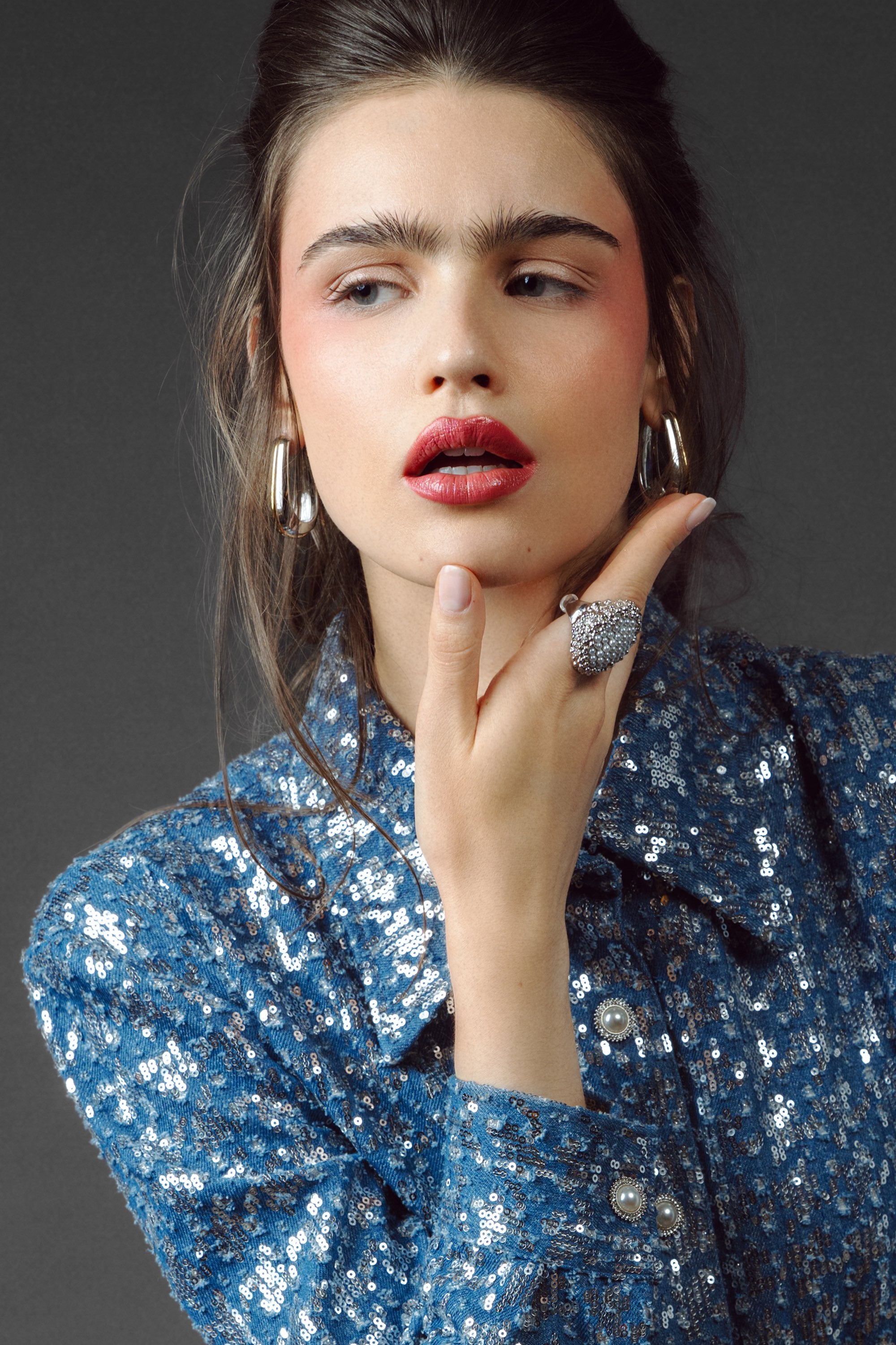 Woman wearing a blue sequin dress with a dark background