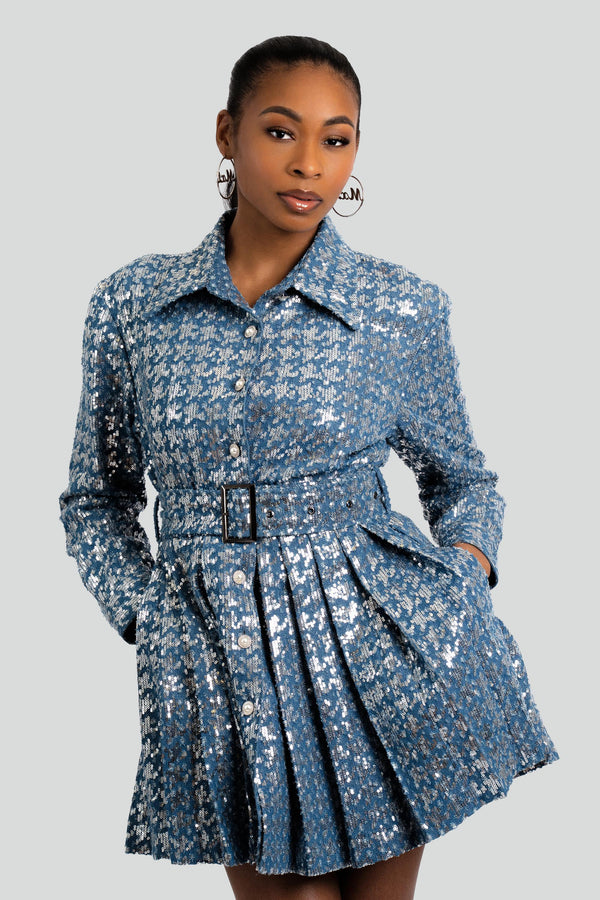 A macro close-up view of a blue denim garment completely overlaid with light-reflecting sequins, detailing the polished pearl crystal buttons running down the center placket