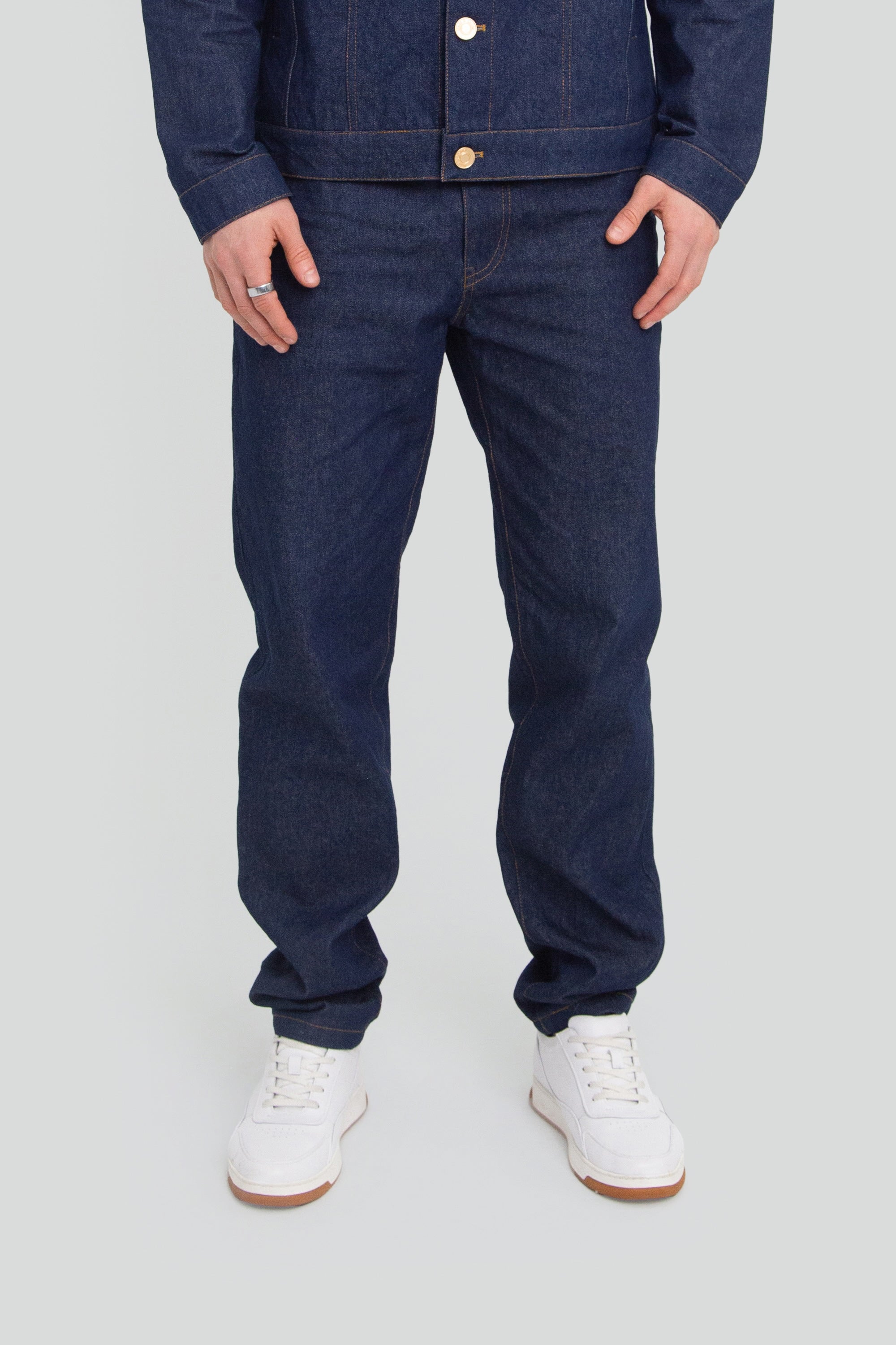 Person wearing a dark blue denim pants on a plain background