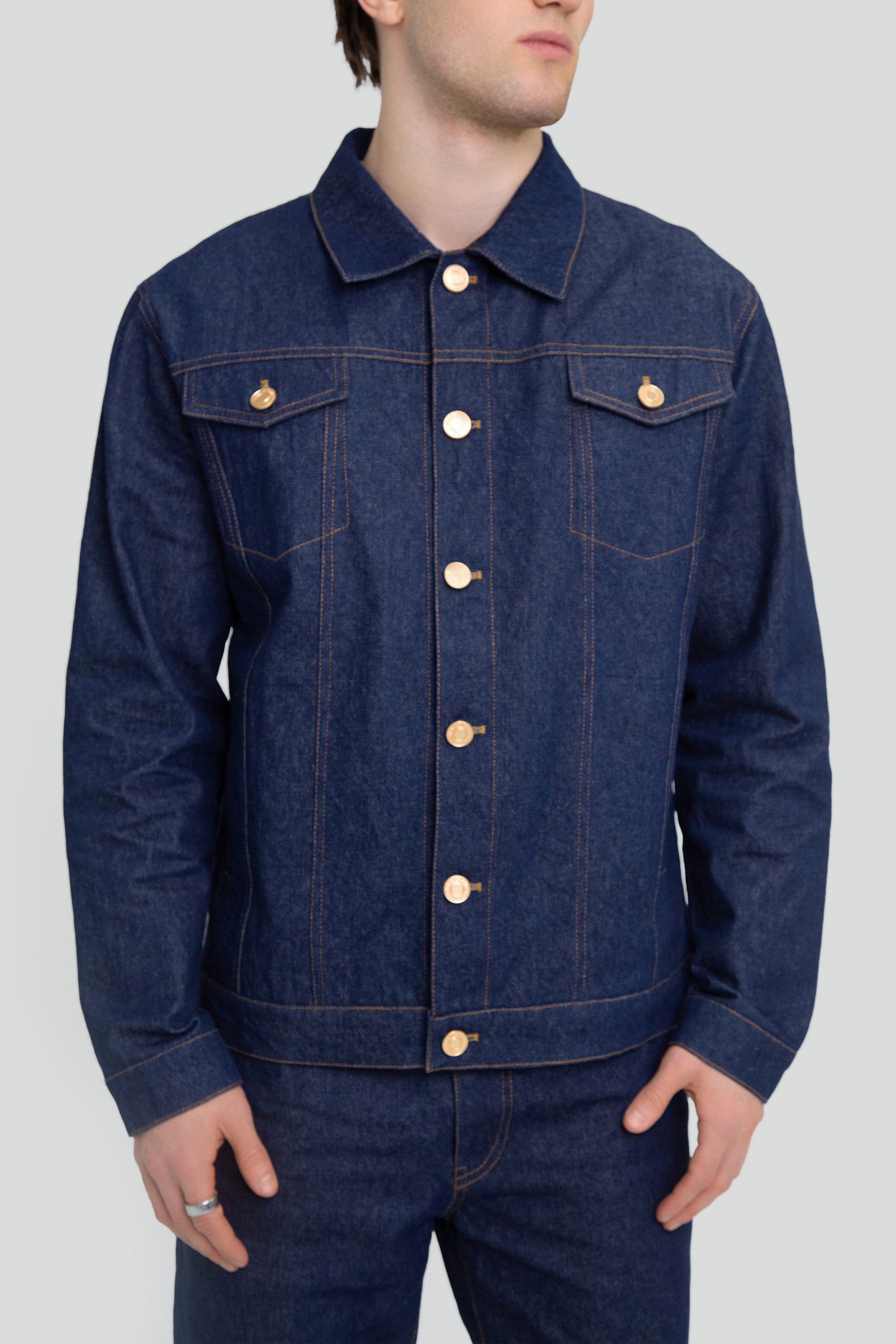Person wearing a blue denim jacket on a plain background