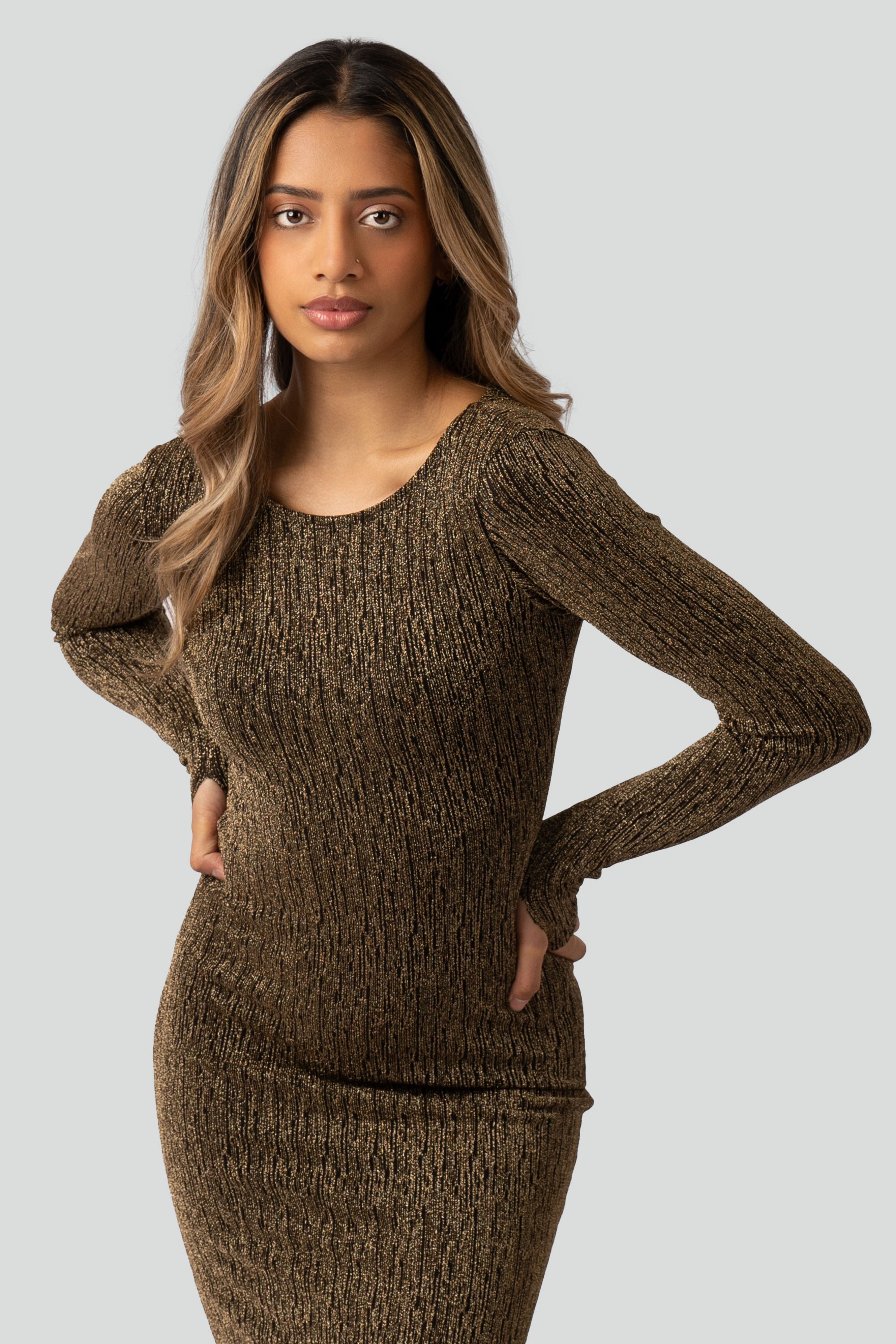 Woman wearing a gold long-sleeve dress on a gray background