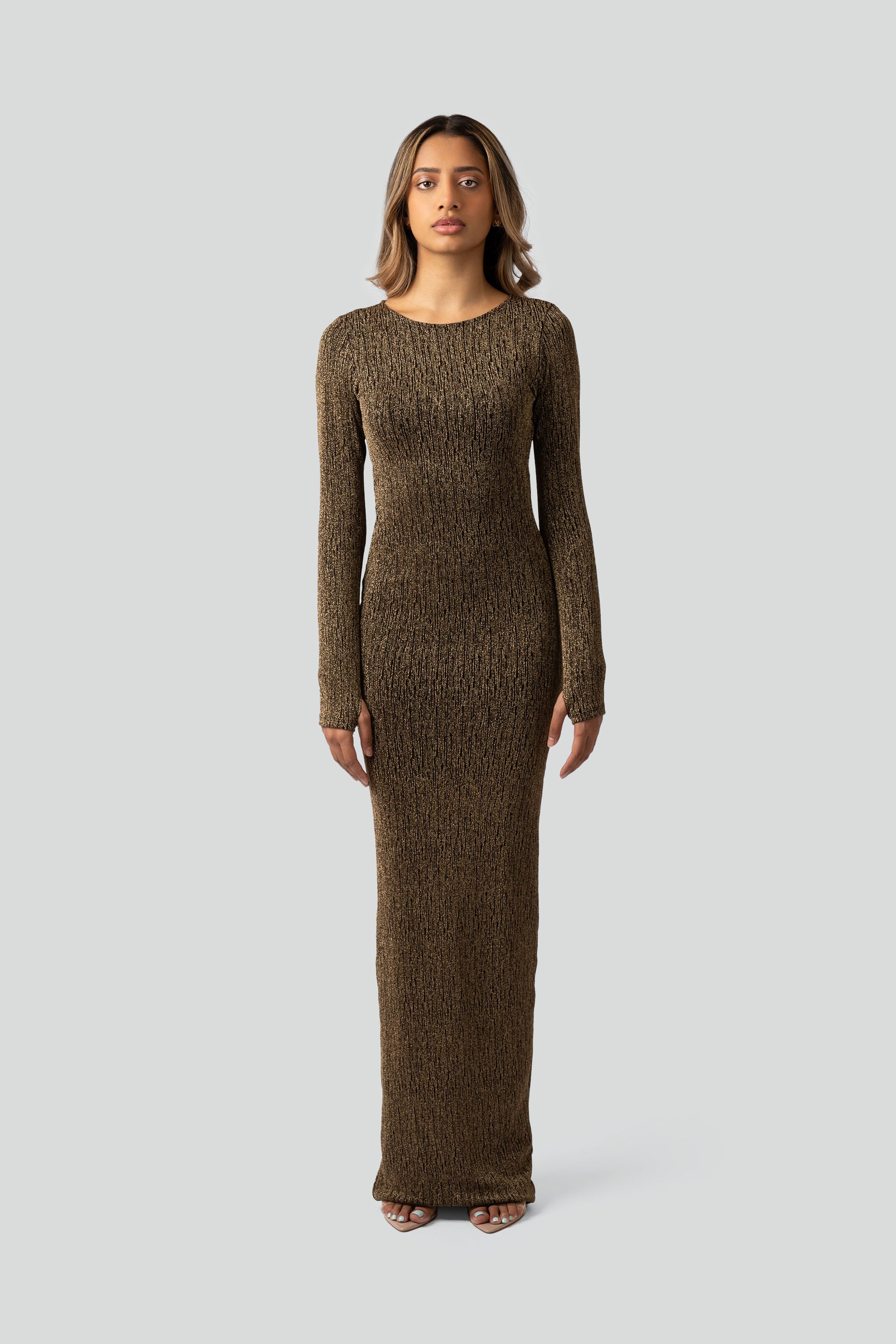 Woman wearing a gold long-sleeve dress on a gray background