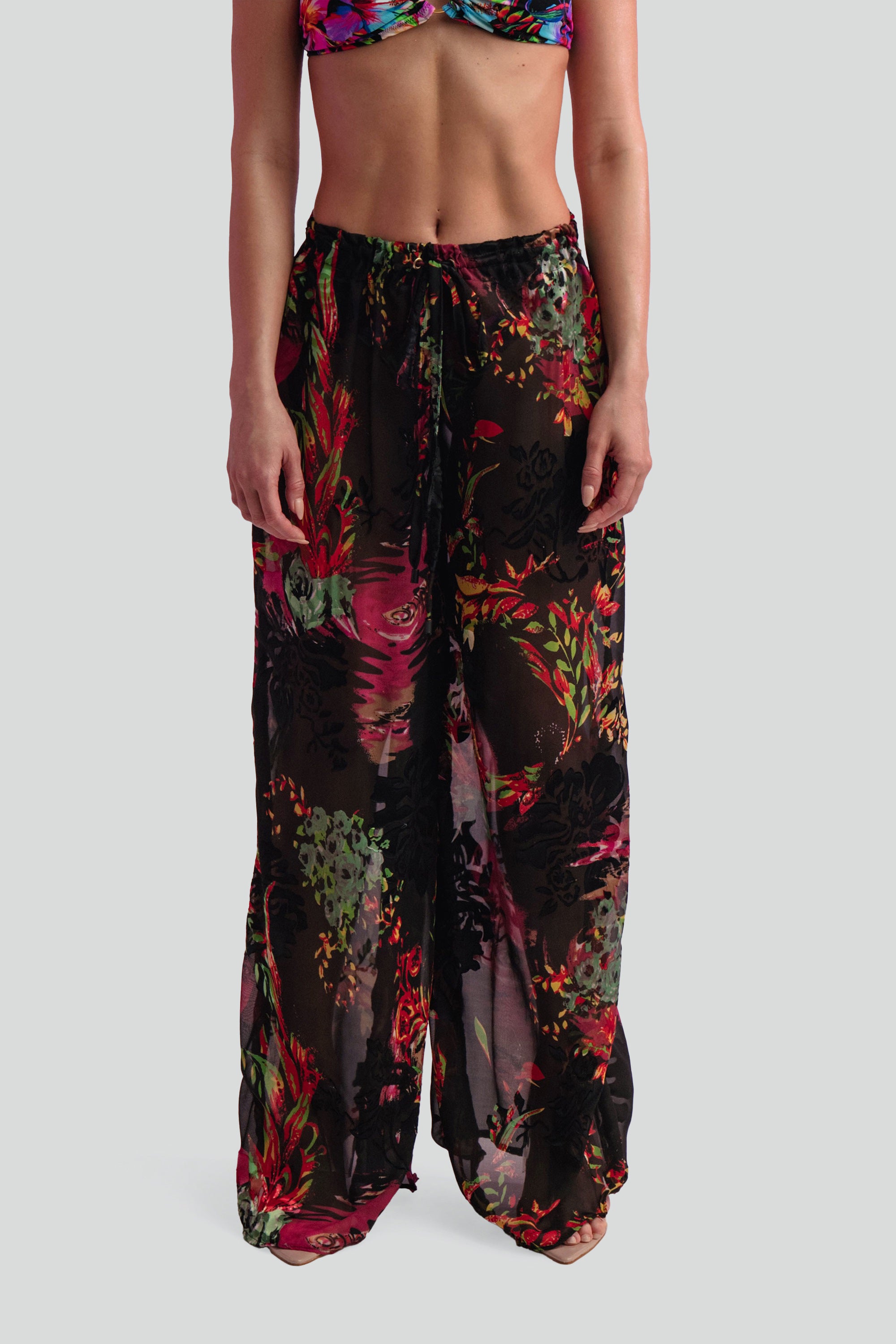 Multicolored floral pants worn by a person on a white background