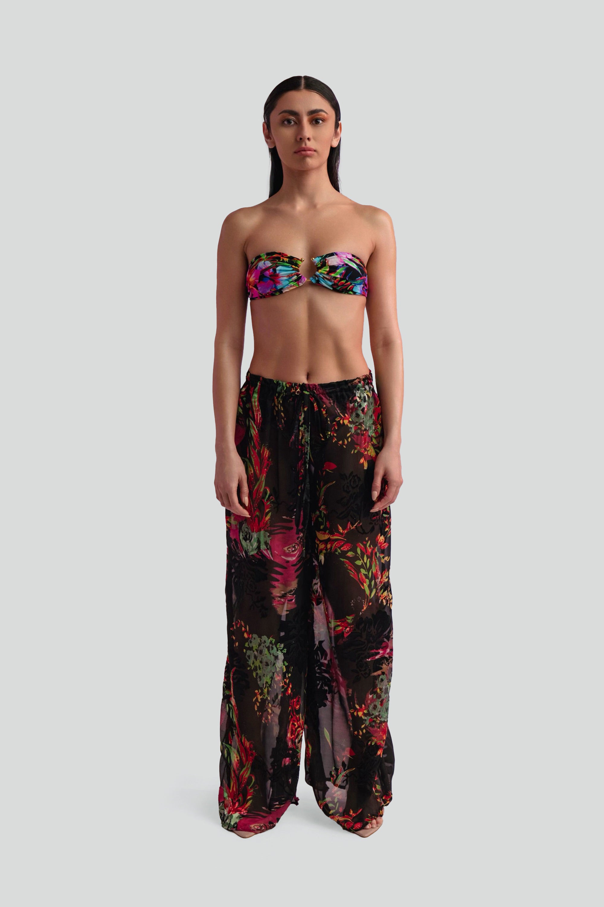 Woman wearing a floral bandeau top and wide-leg pants on a white background