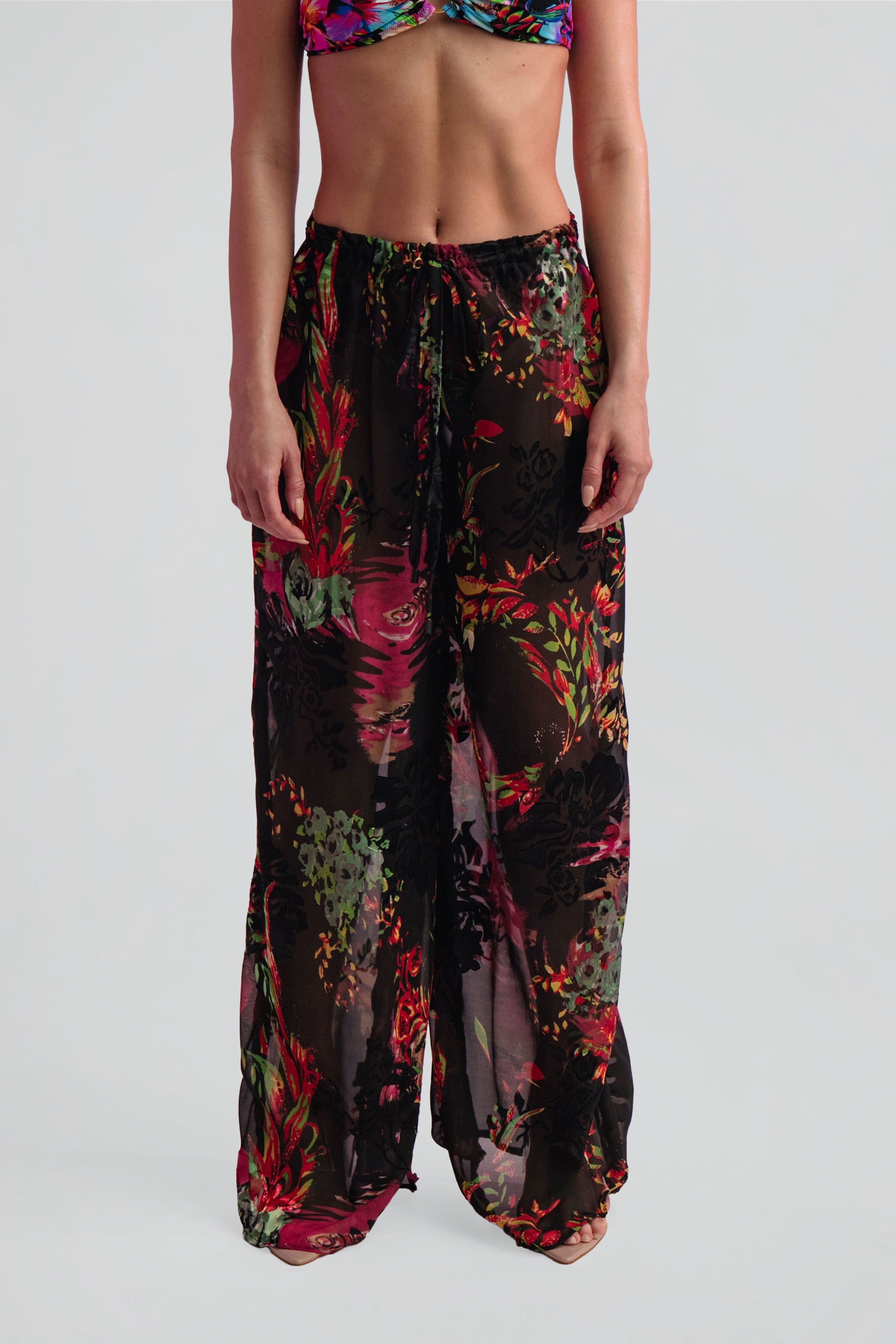 Multicolored floral pants worn by a person on a white background
