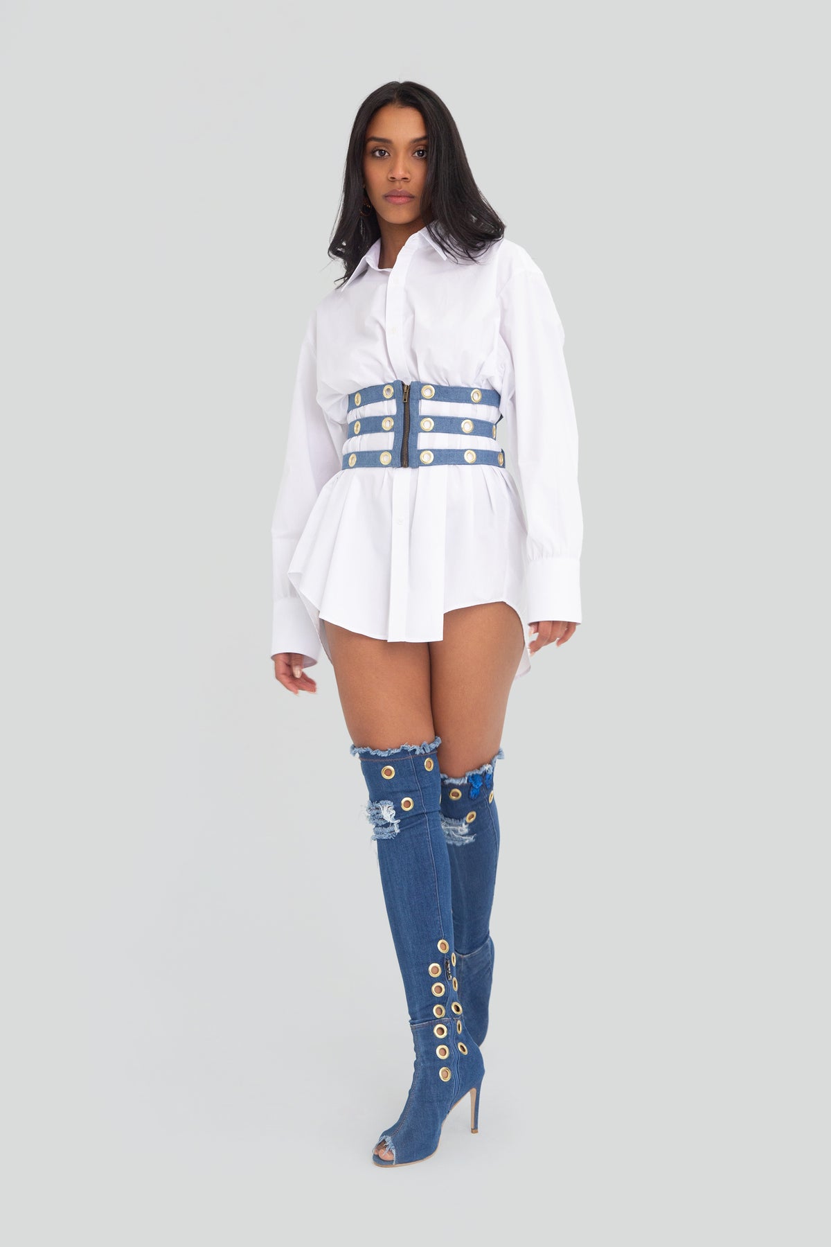 Woman wearing a light blue denim corset belt featuring a structured lace up design and metallic grommet detailing