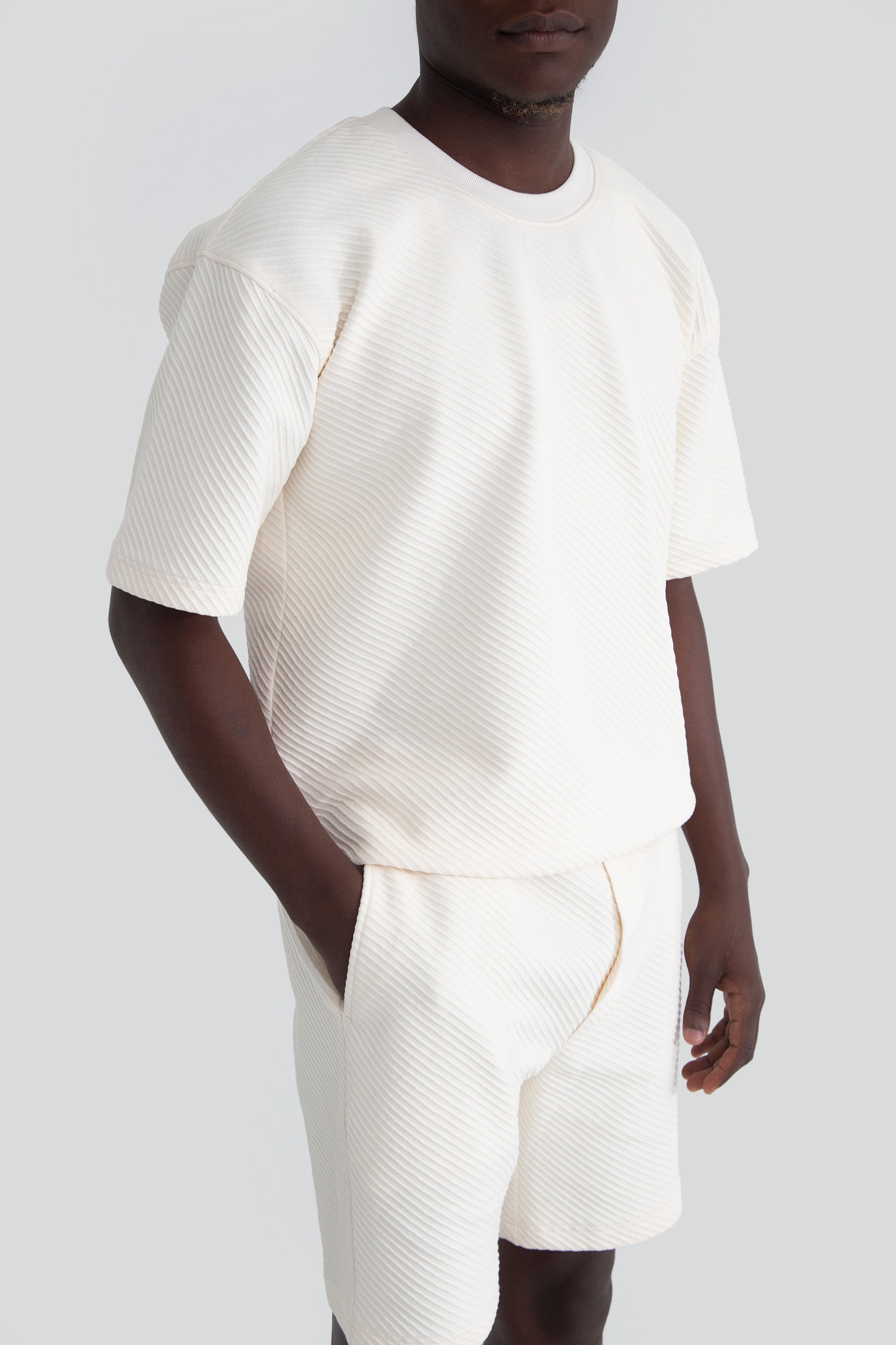 Person wearing a white top and shorts on a plain background