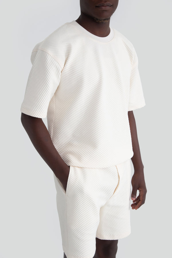 Close up view of premium off white structured rib knit fabric highlighting the heavy texture on a luxury loungewear top