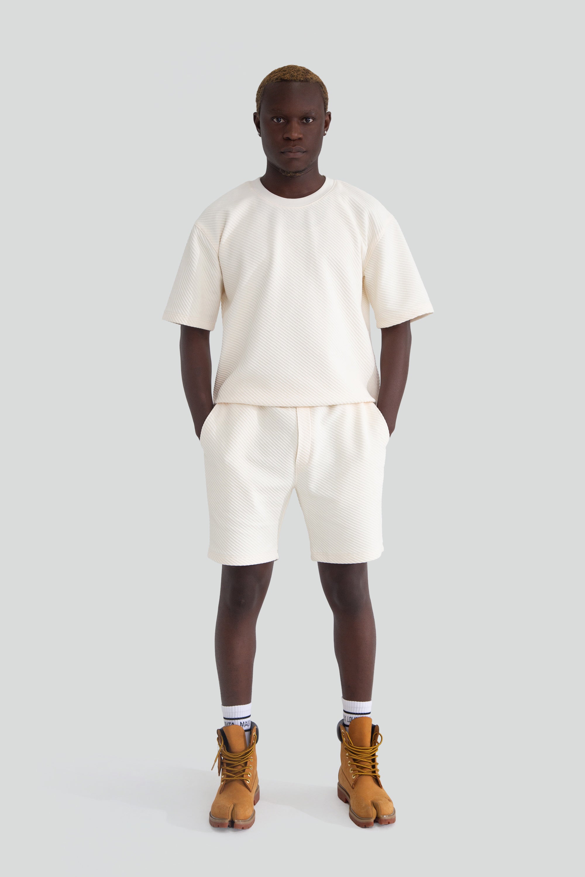 Person wearing a white top and shorts on a plain background