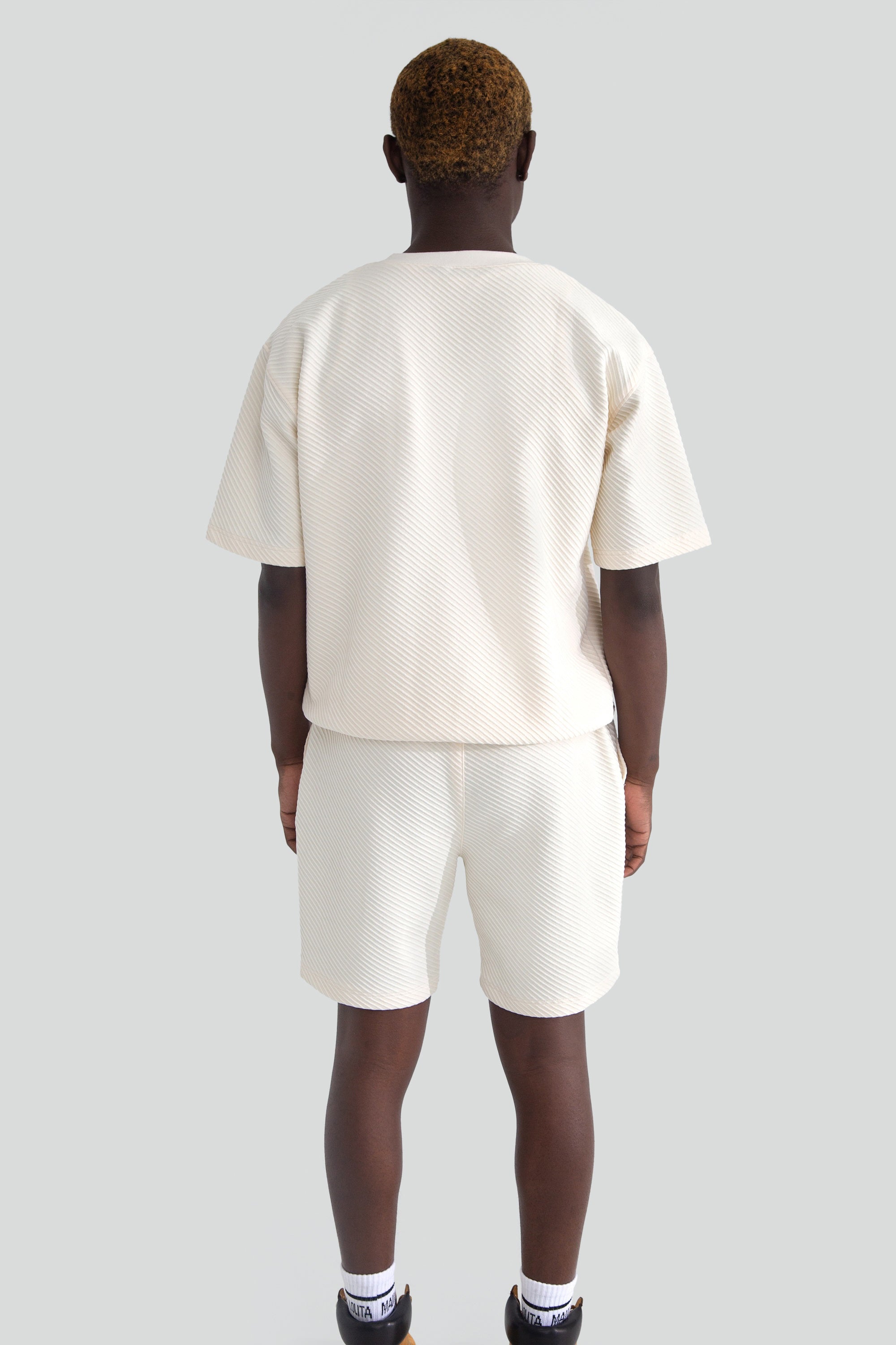Person wearing a white top and shorts on a plain background
