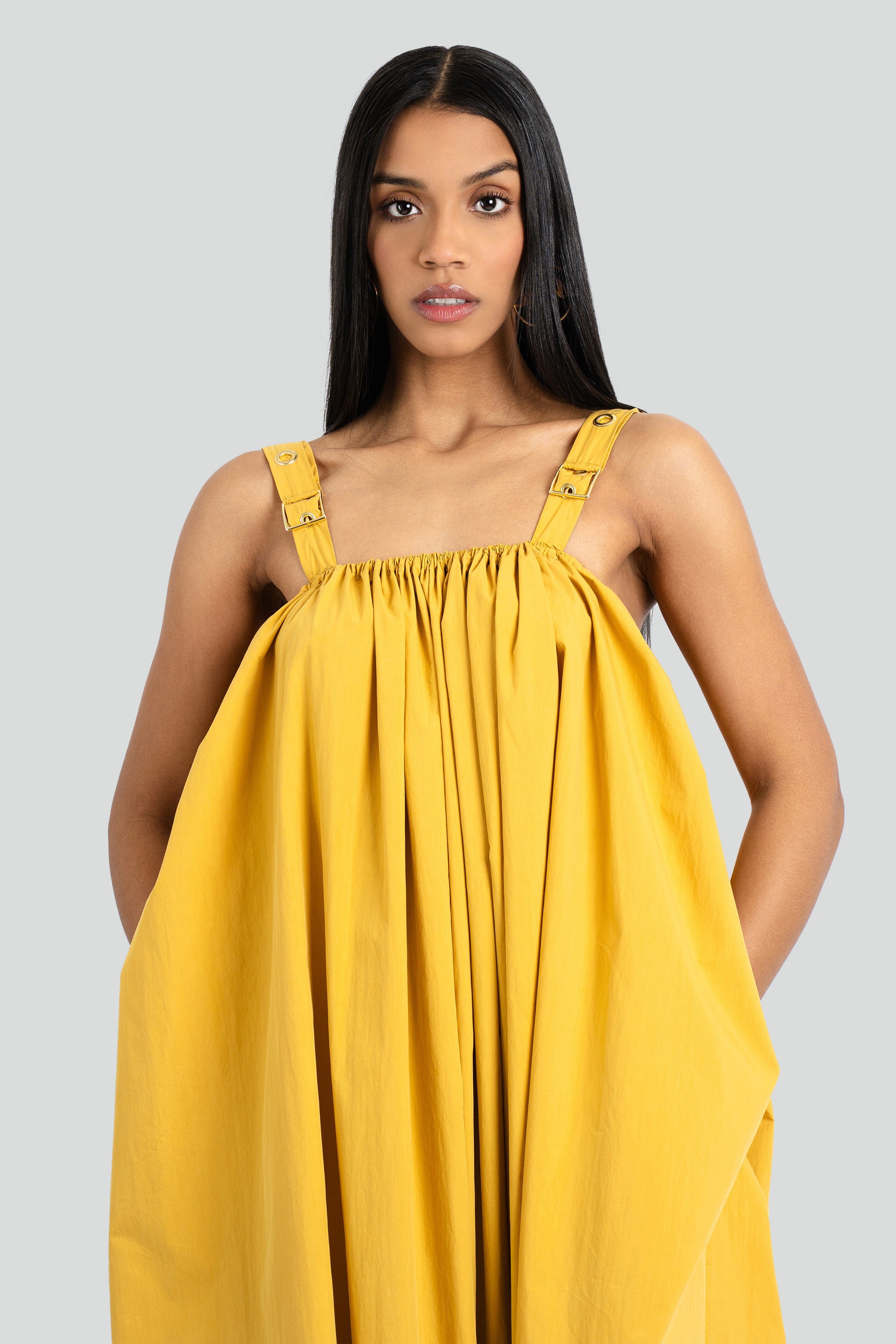 Model wearing a yellow dress against a white background