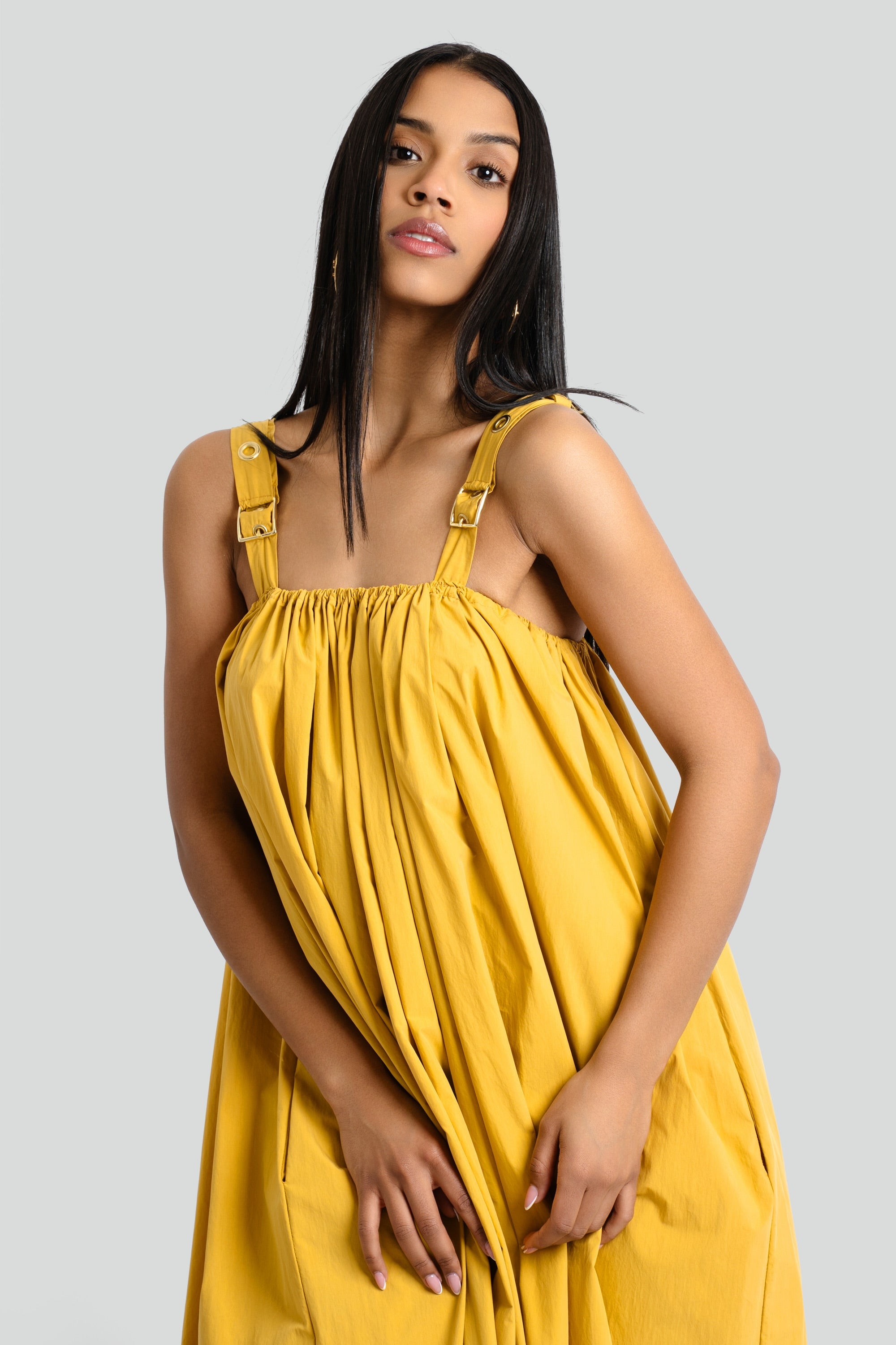 Woman wearing a mustard yellow bohemian maxi dress with a gathered neckline, golden grommets, and textured eyelet detailing by Maui X Lolita