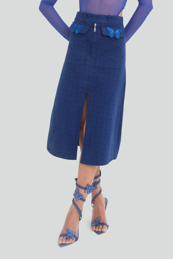 Woman wearing a light blue suede treated denim pencil skirt featuring utility front flap pockets and a clean front slit hem