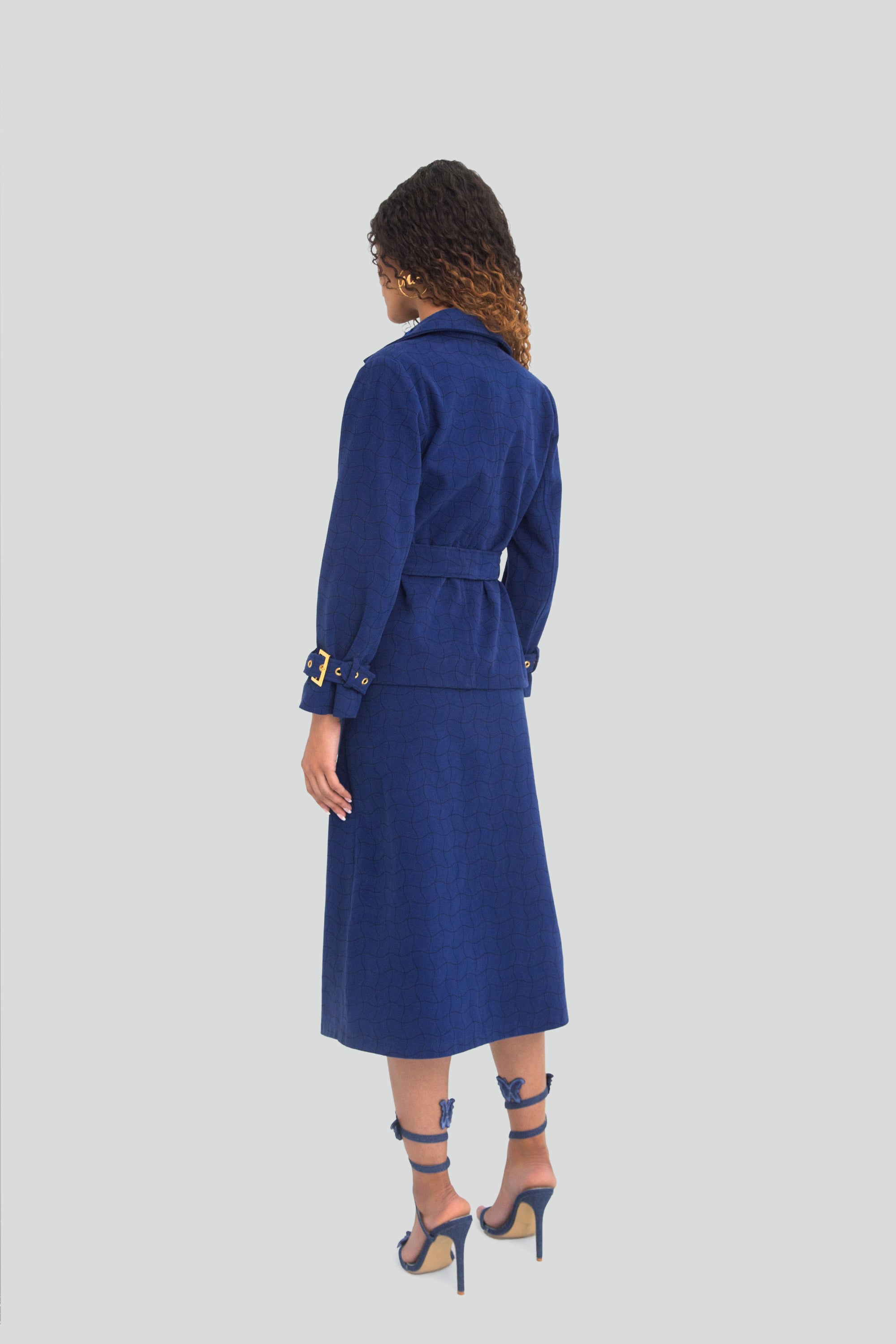 Woman wearing a blue coat and skirt set on a light gray background