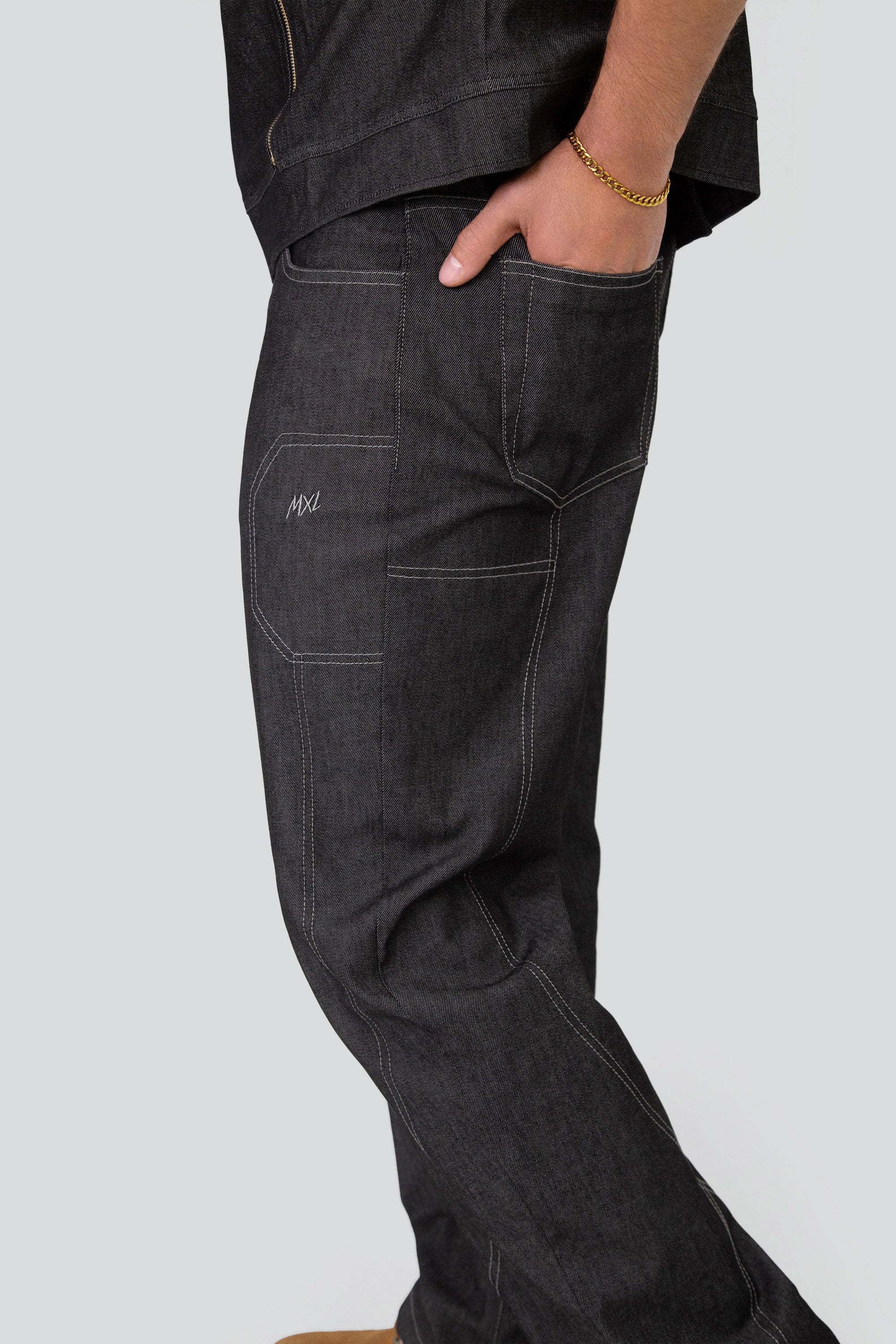 Man wearing a grey denim mock neck vest and matching pants on a plain background