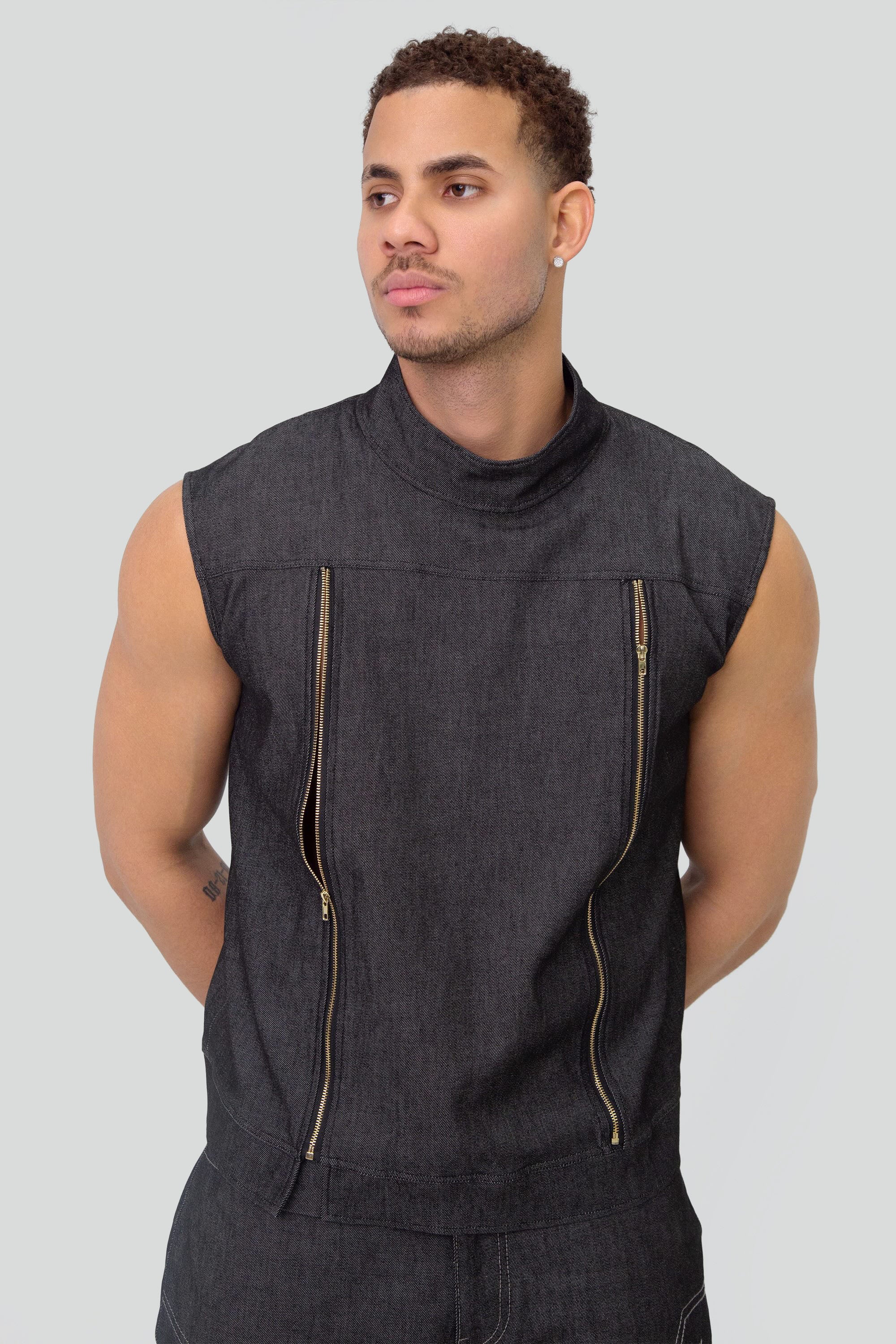 Man wearing a grey denim mock neck vest and matching pants on a plain background