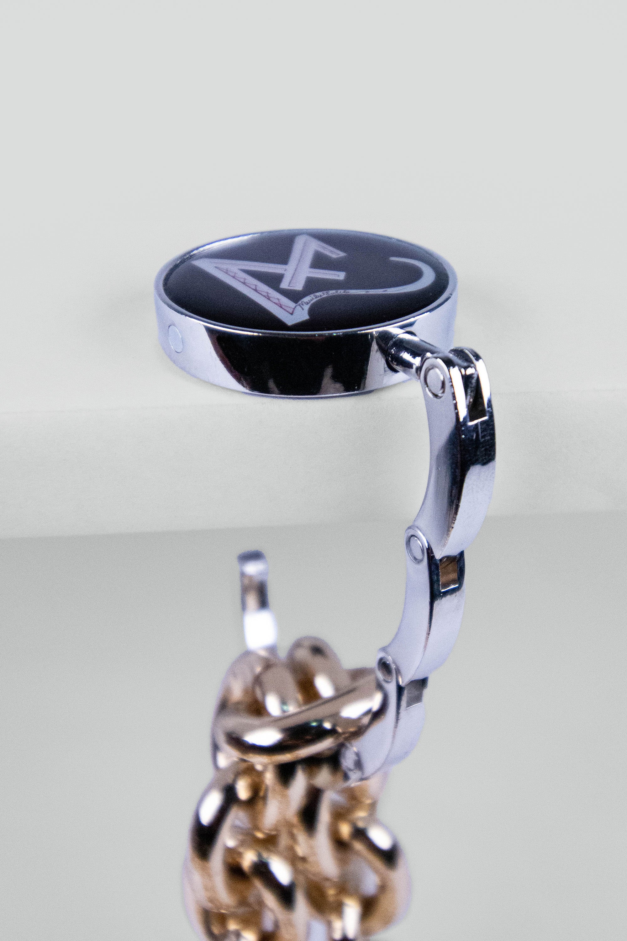 Close-up of a metallic purse hook with a chain on a light gray background