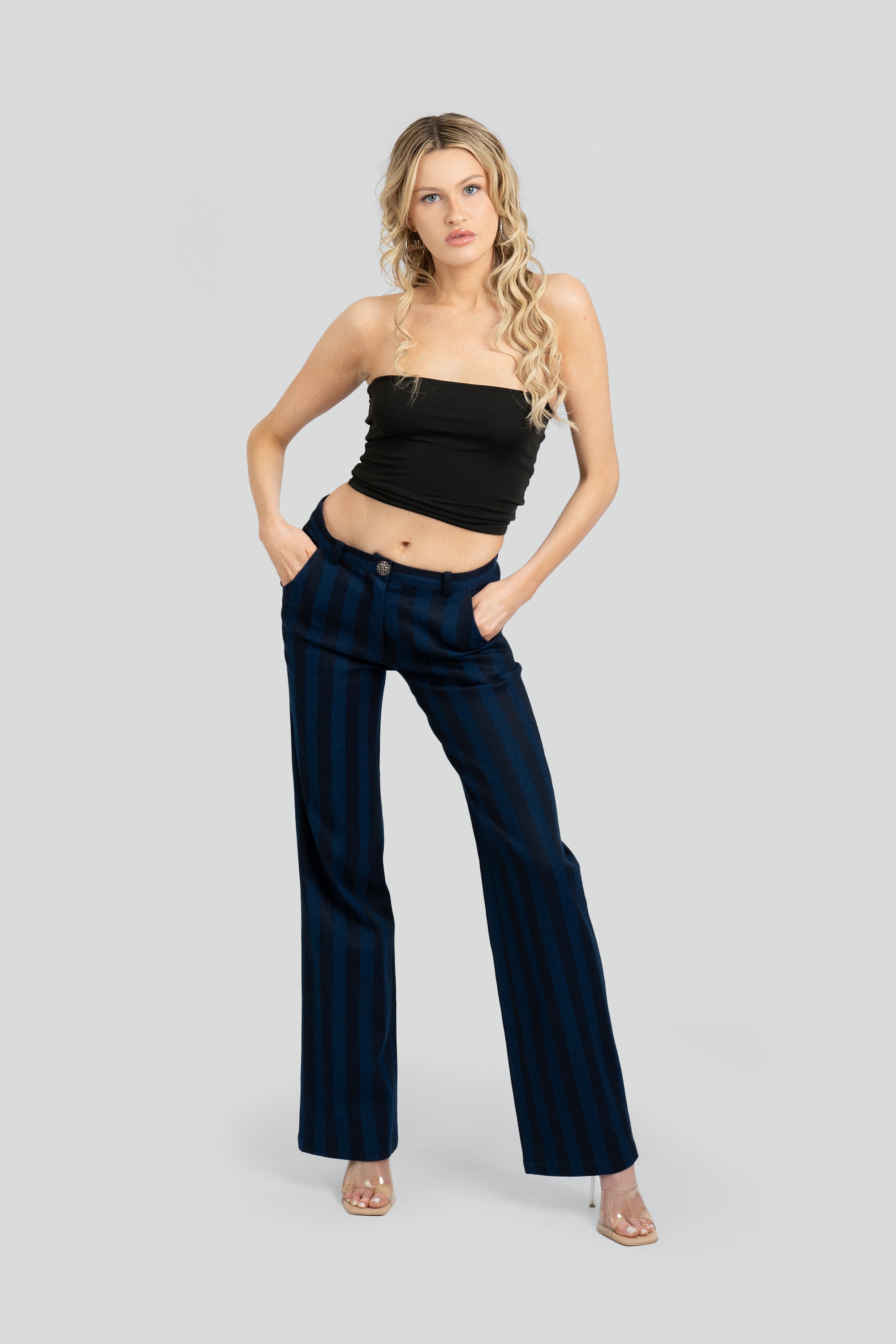 Woman wearing a black tube top and navy striped pants on a white background