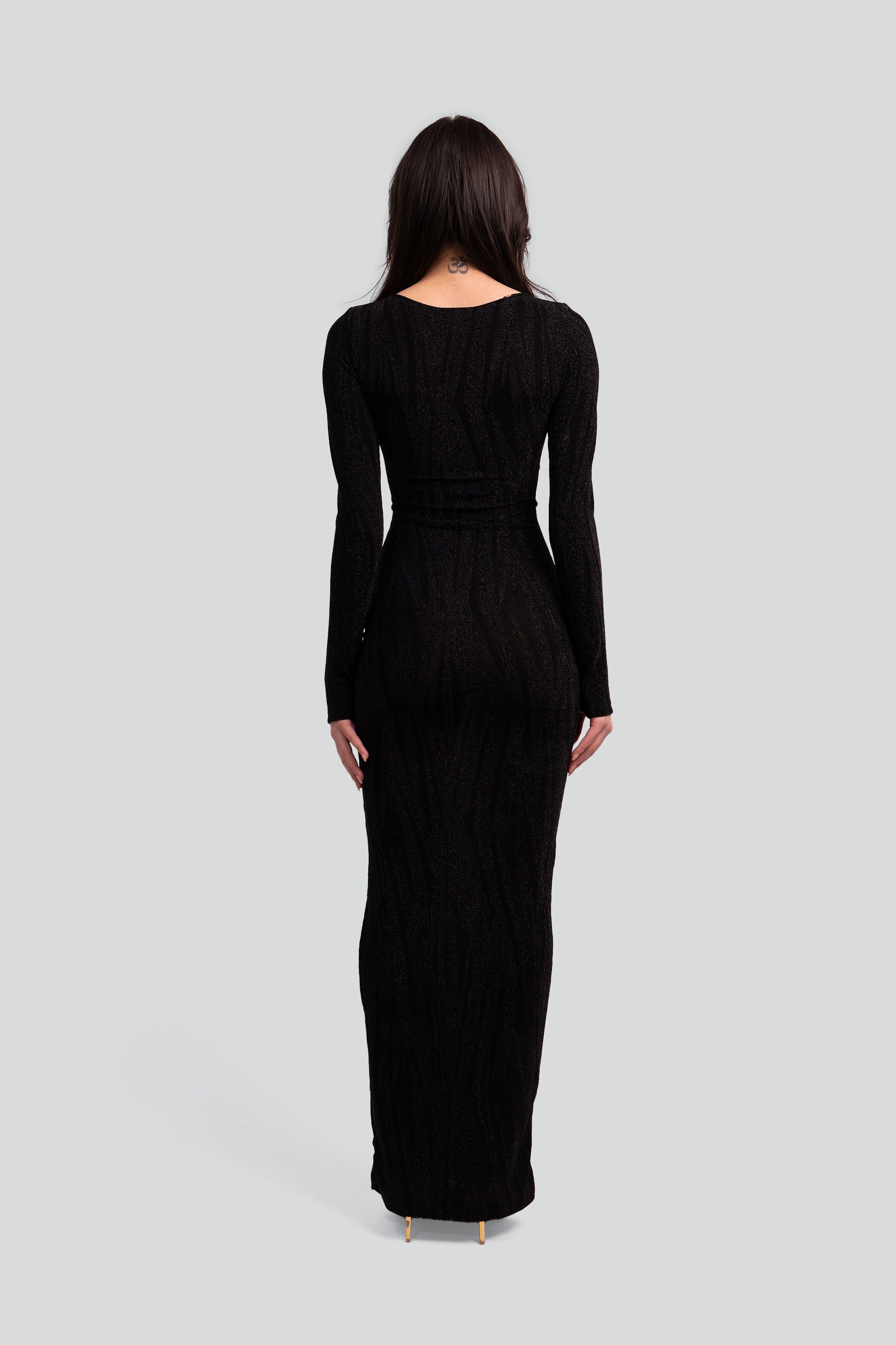 Back view of a woman wearing a black patterned dress on a gray background
