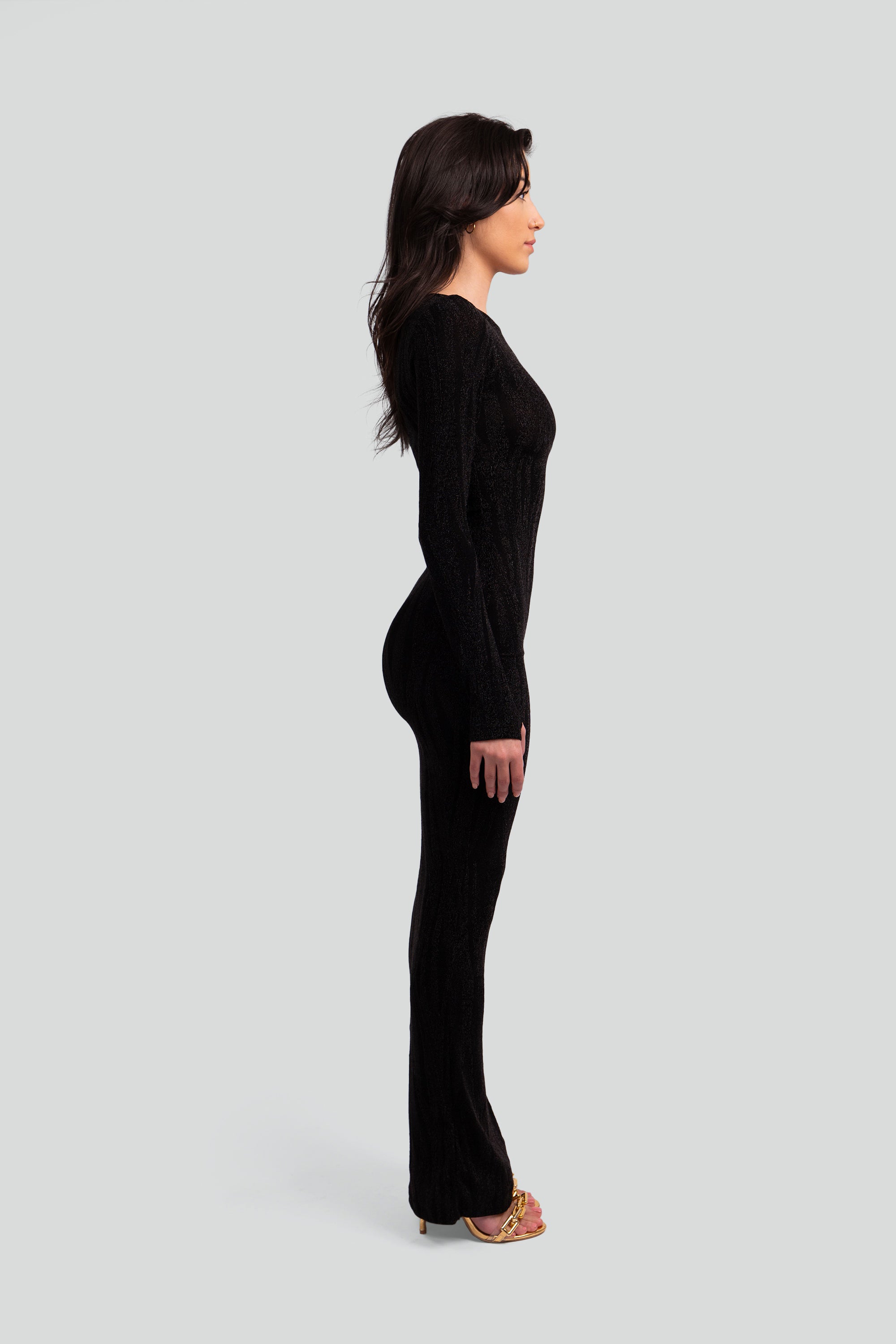 Side view of a woman wearing a black patterned dress on a gray background