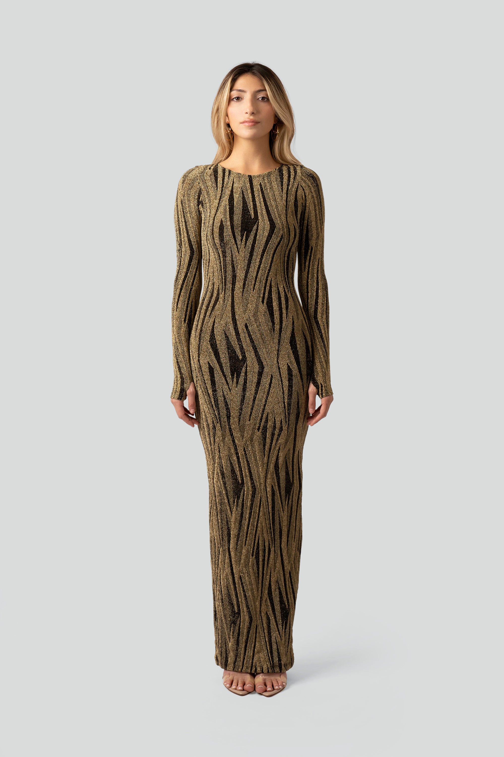 Woman wearing a gold and black patterned dress on a gray background