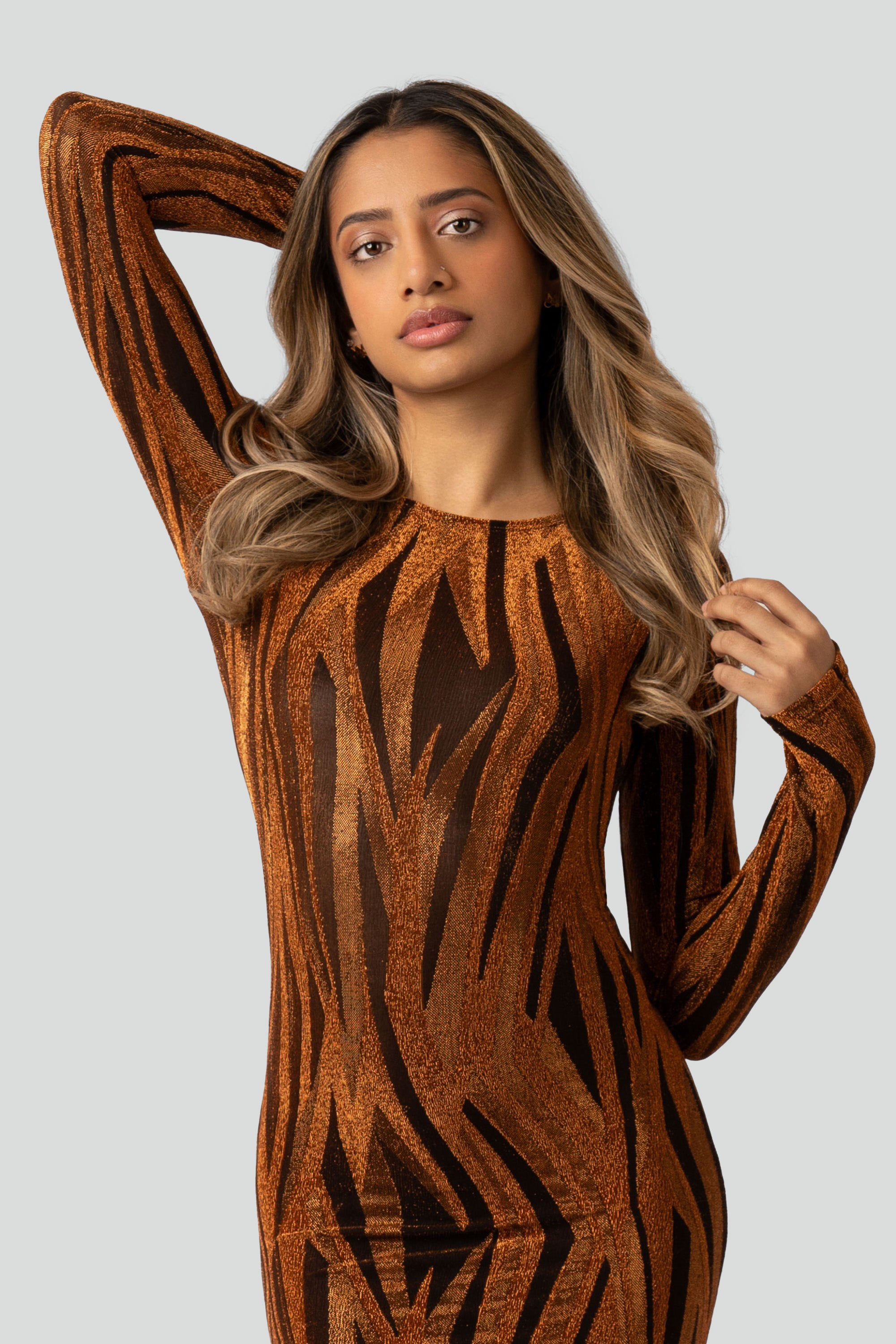 Woman wearing an orange and black patterned dress on a gray background
