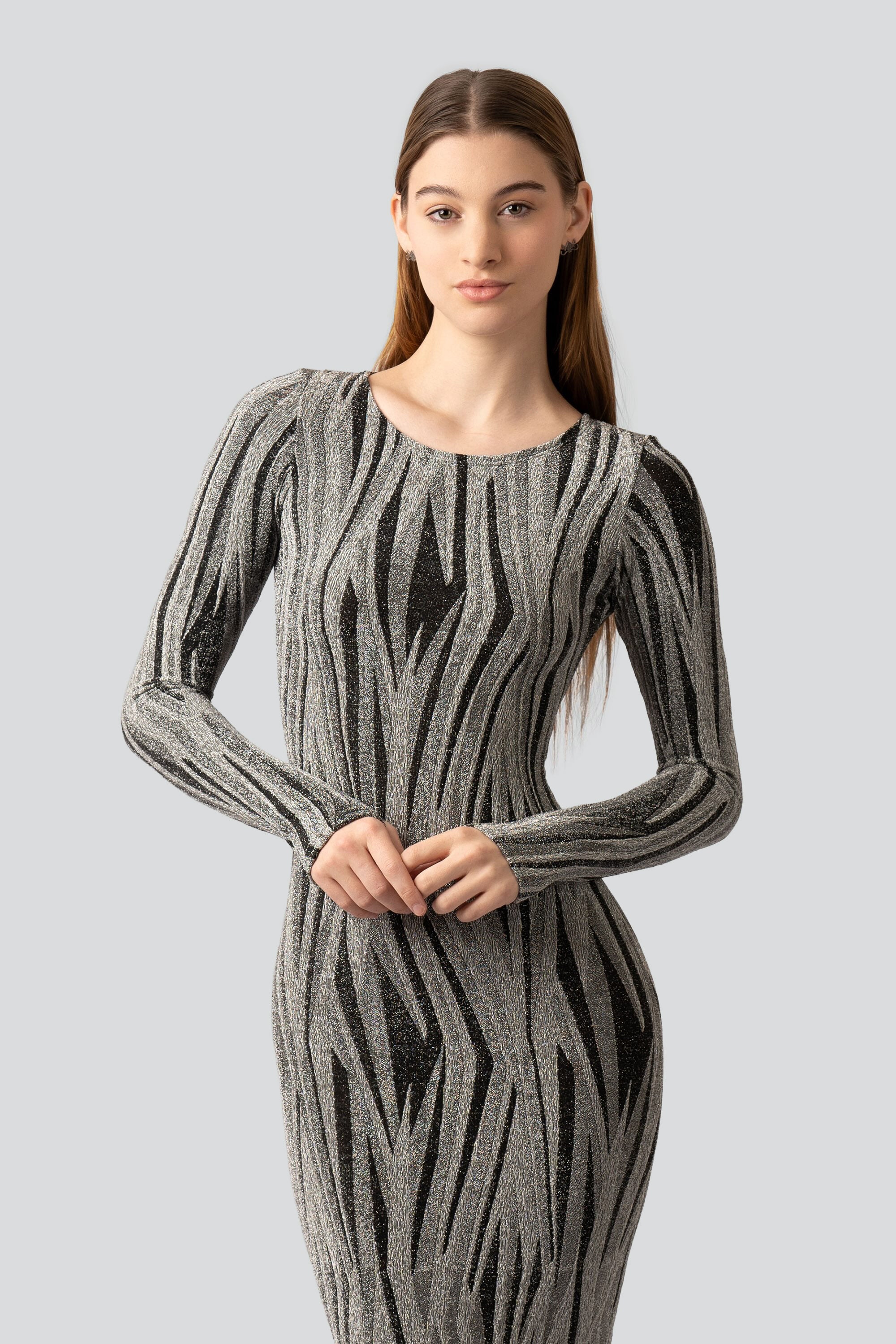 Woman wearing a silver and black patterned dress on a gray background