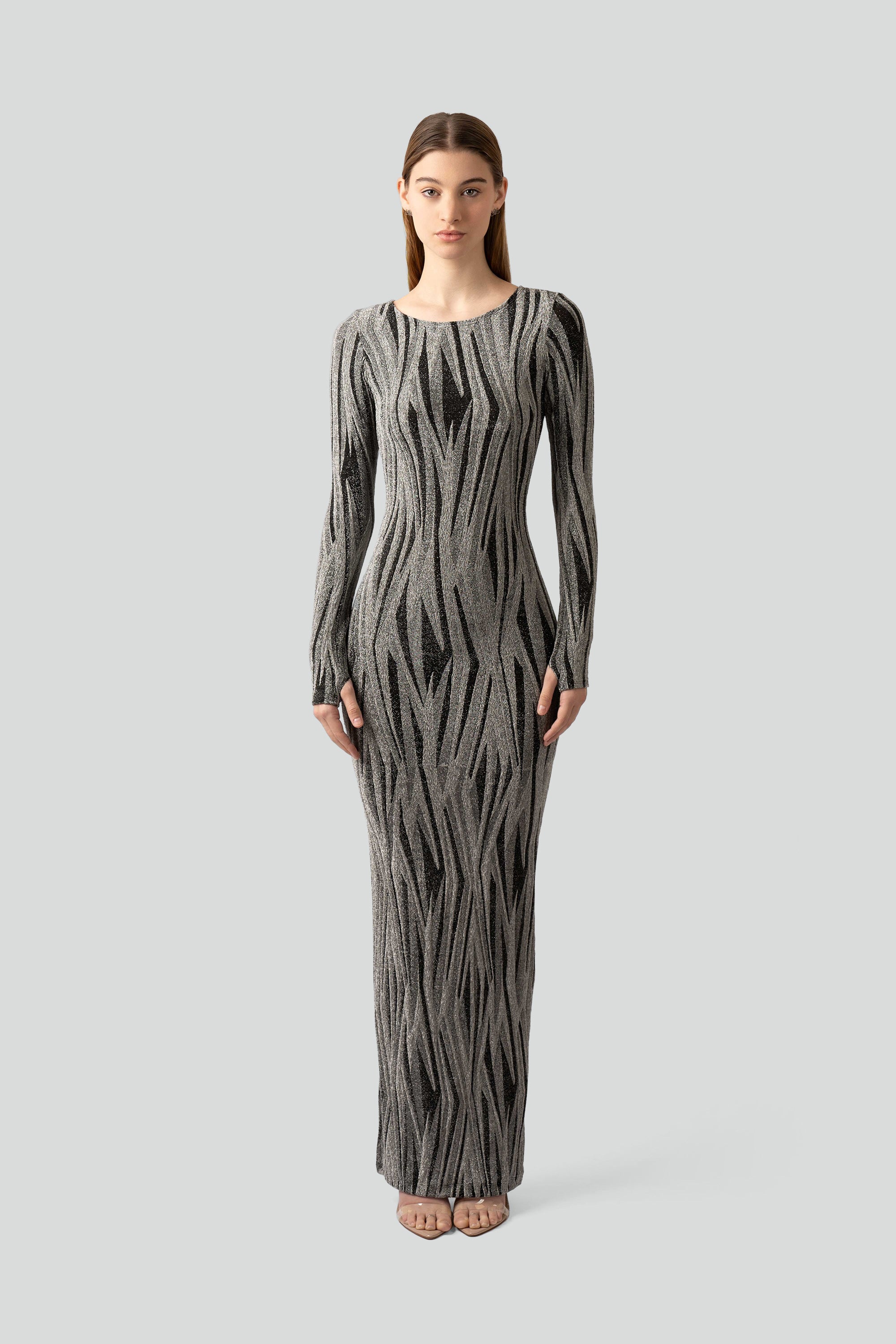 Woman wearing a silver and black patterned dress on a gray background