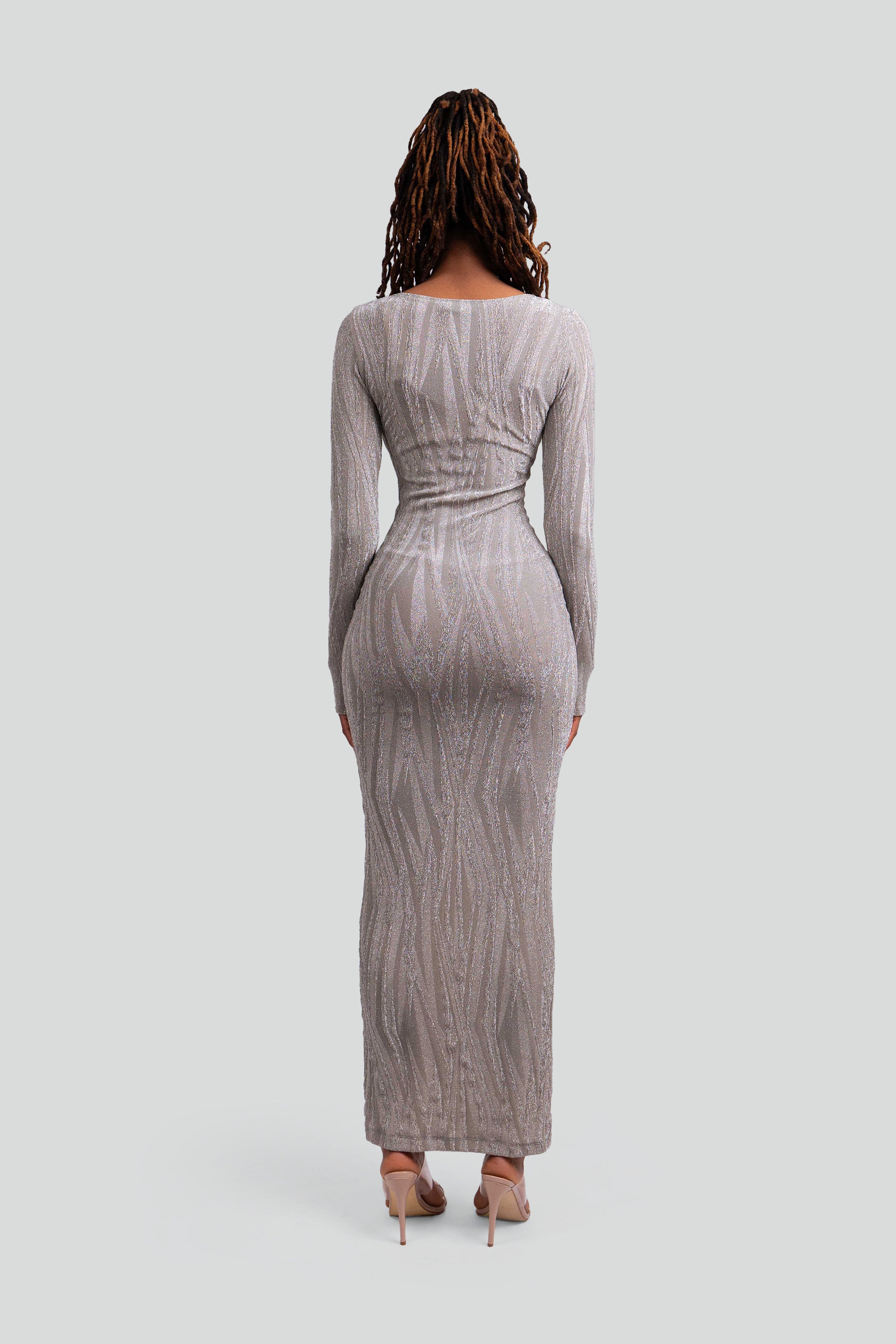 Back view of a woman wearing a silver patterned dress on a gray background