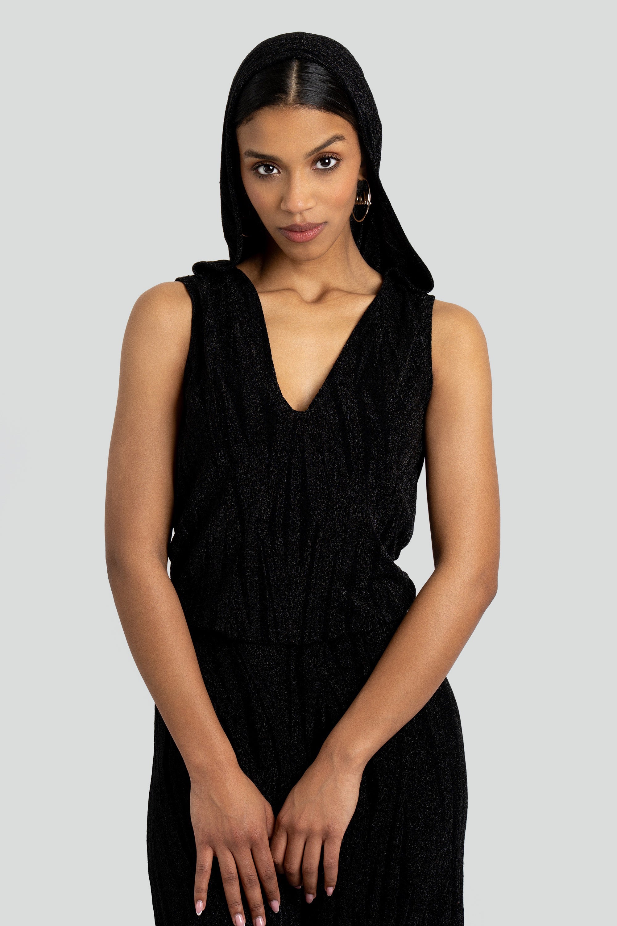 Close up of a woman wearing a black hooded jumpsuit on a white background