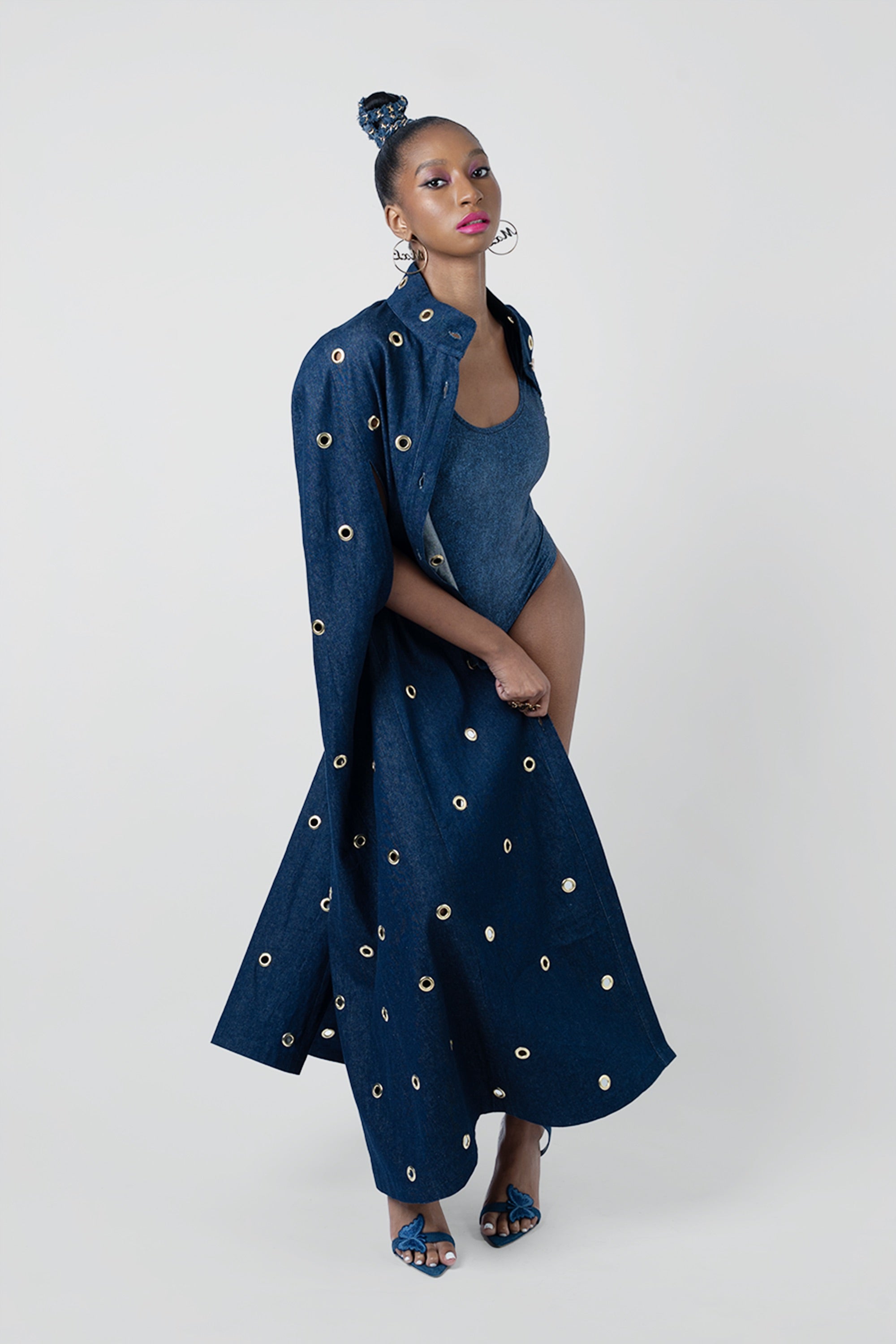 Woman wearing a long dark blue dress with gold embellishments on a white background