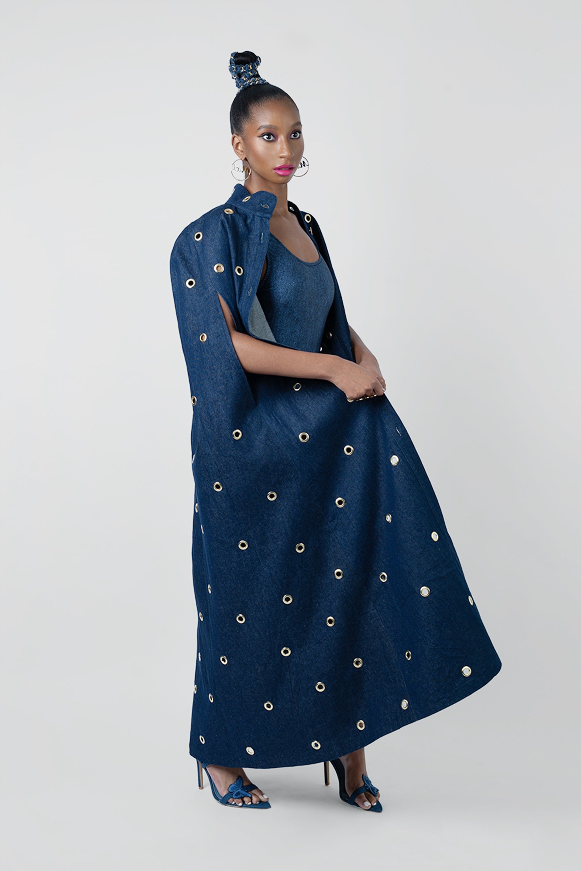 Woman wearing a long dark blue dress with gold embellishments on a white background