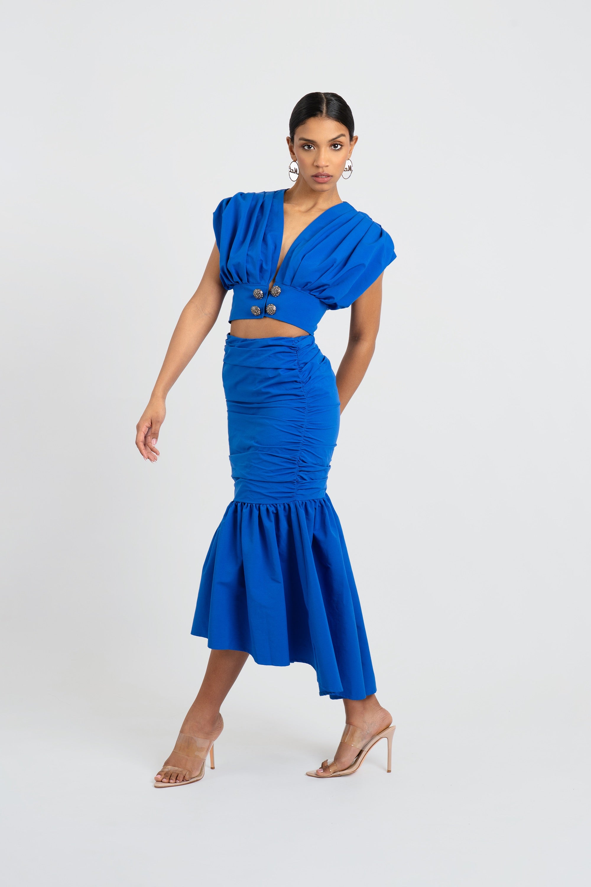 Woman wearing a blue outfit with a fitted top and skirt on a white background