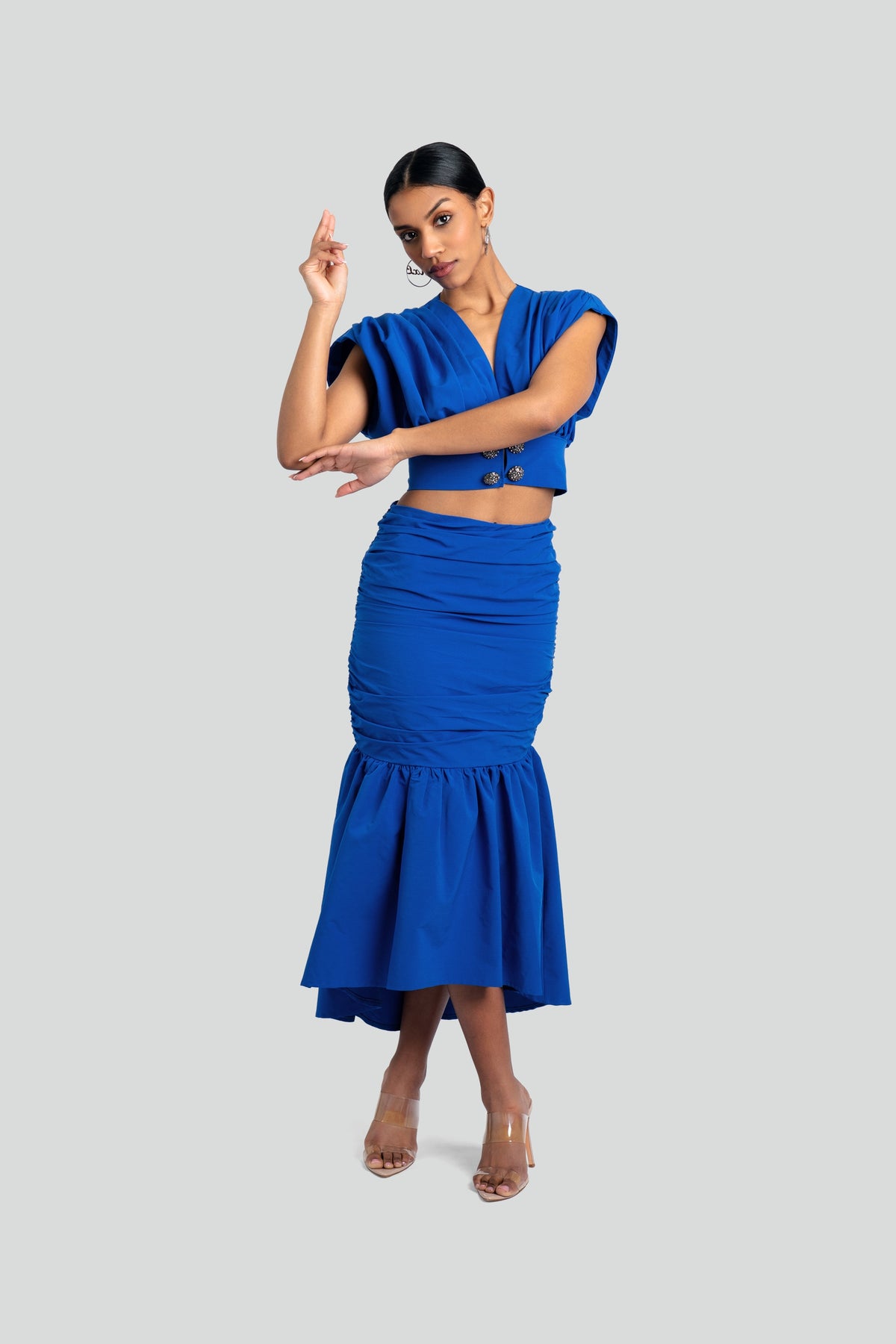 Woman wearing a blue two-piece ruched skirt set by Maui X Lolita, showcasing an asymmetrical silhouette, statement texture, and a body-sculpting fit