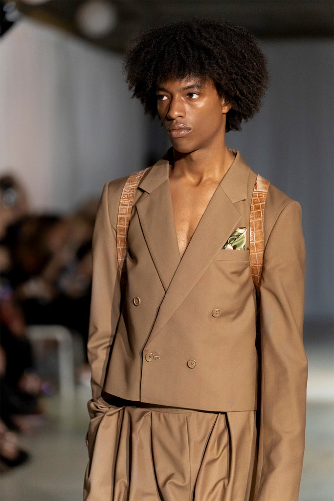 Model wearing a brown suit on the runway