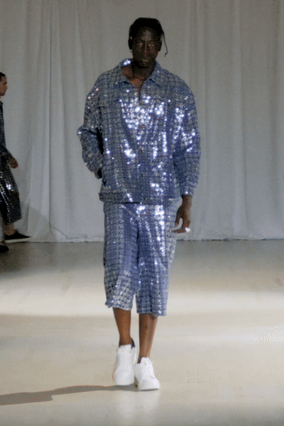 Model wearing a blue sequined denim set walking down the runway
