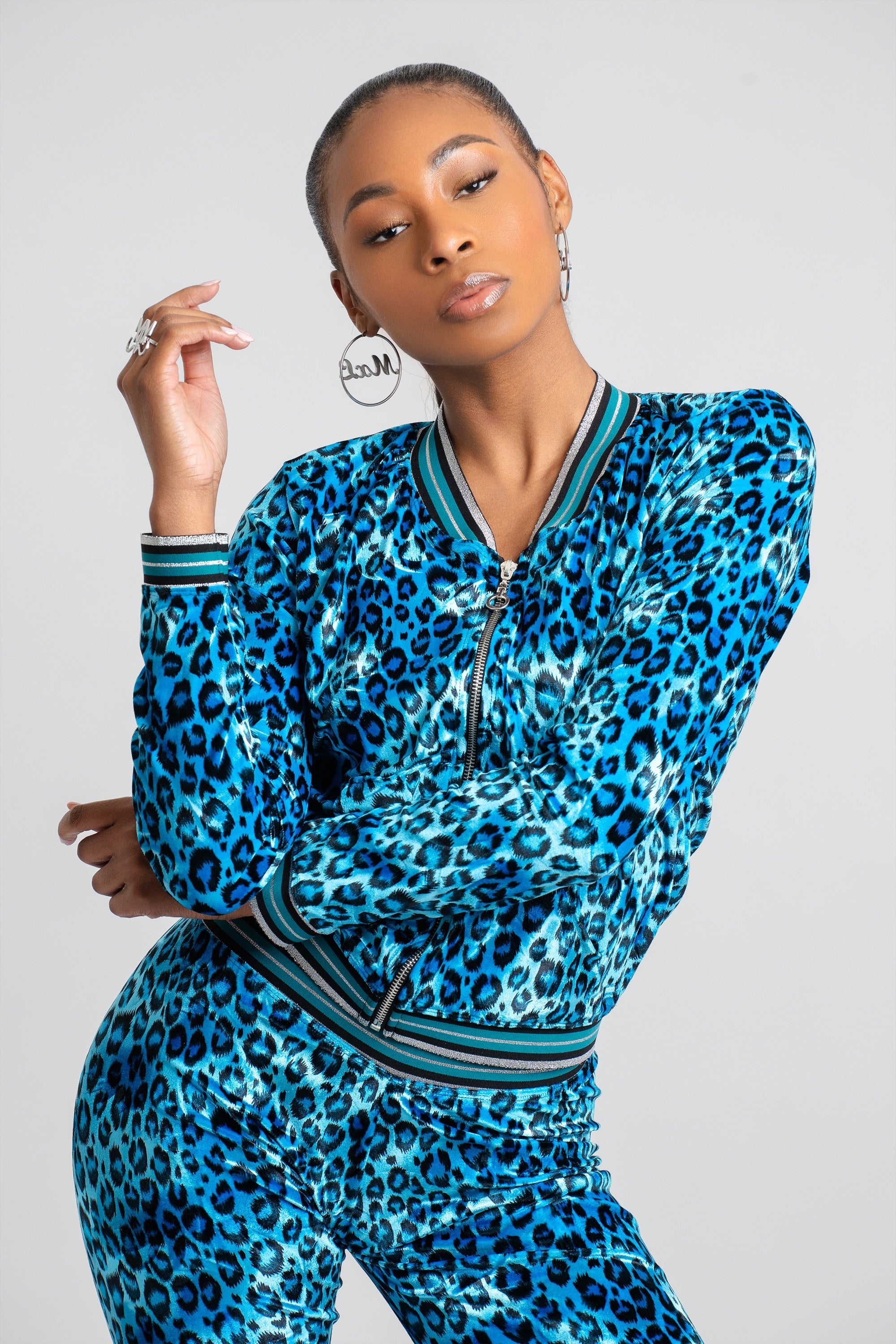 Woman wearing a blue leopard print velour tracksuit on a white background