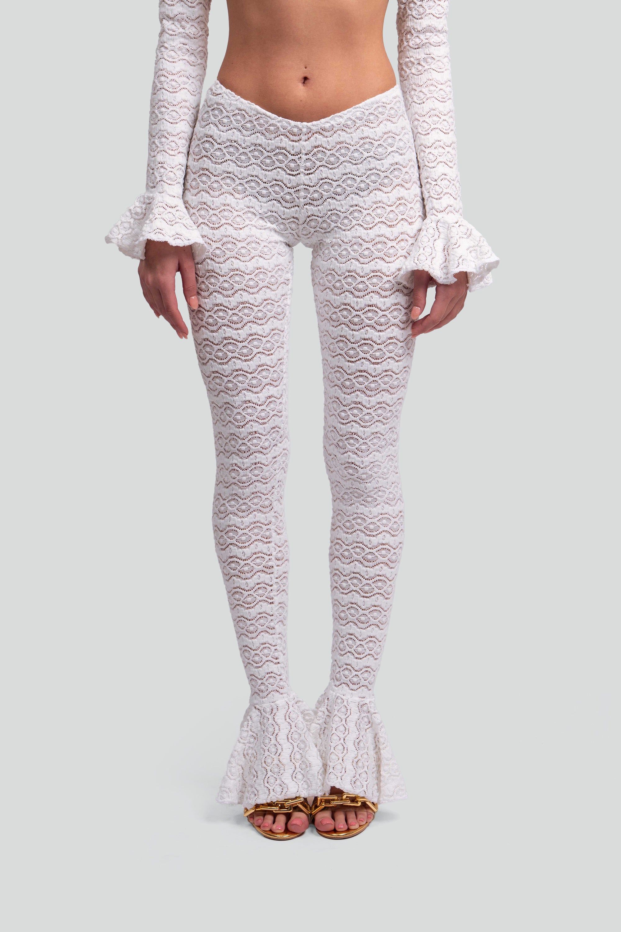 White lace pants with ruffled hem on a gray background