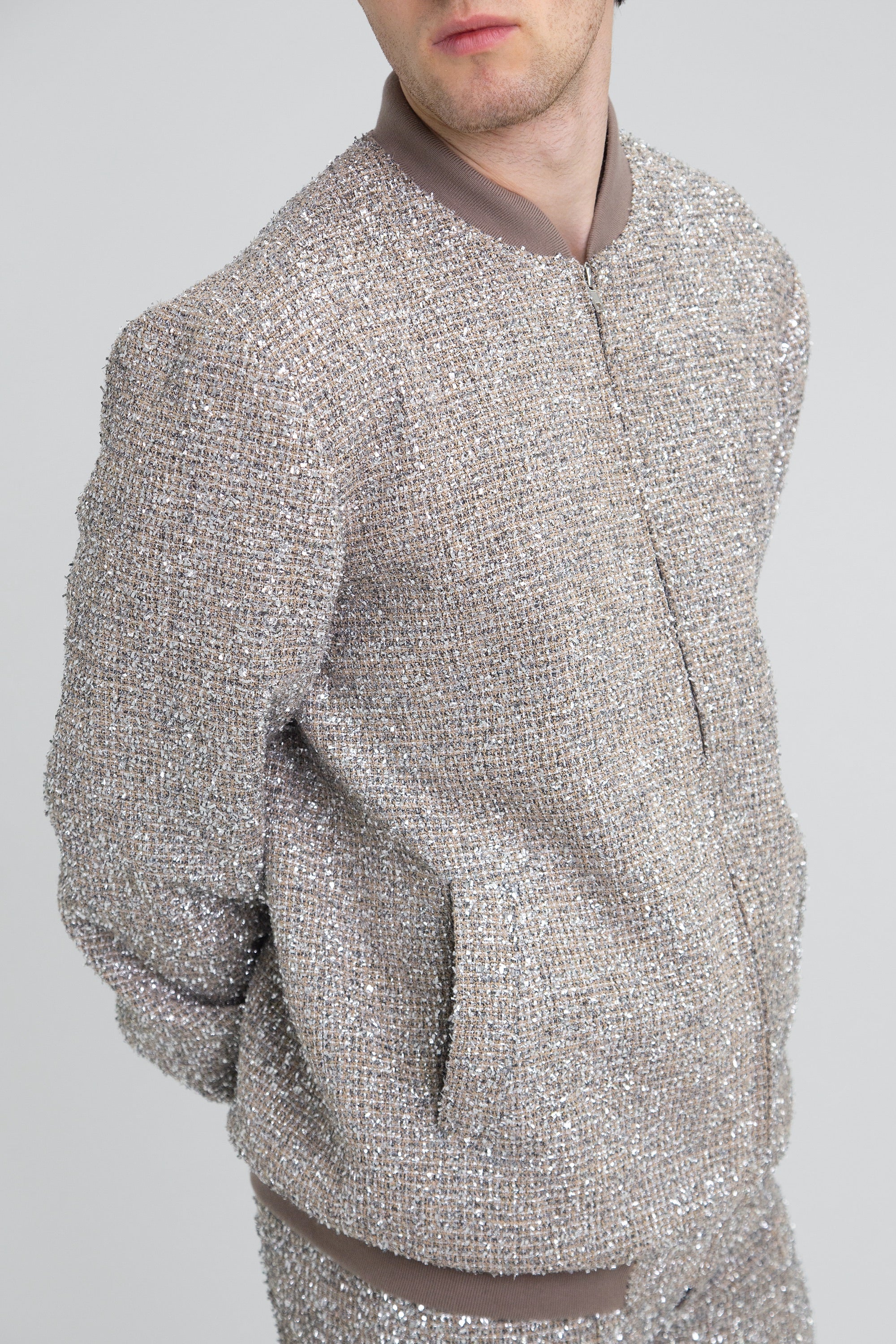 Person wearing a textured silver jacket on a plain background