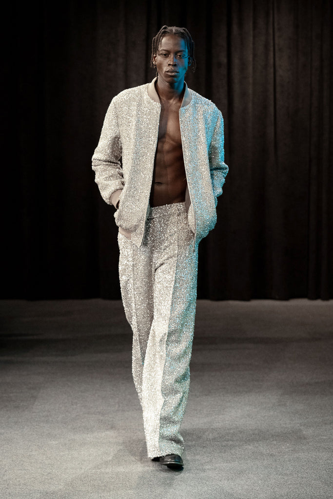 Man wearing a light-colored metallic tweed outfit with a dark background