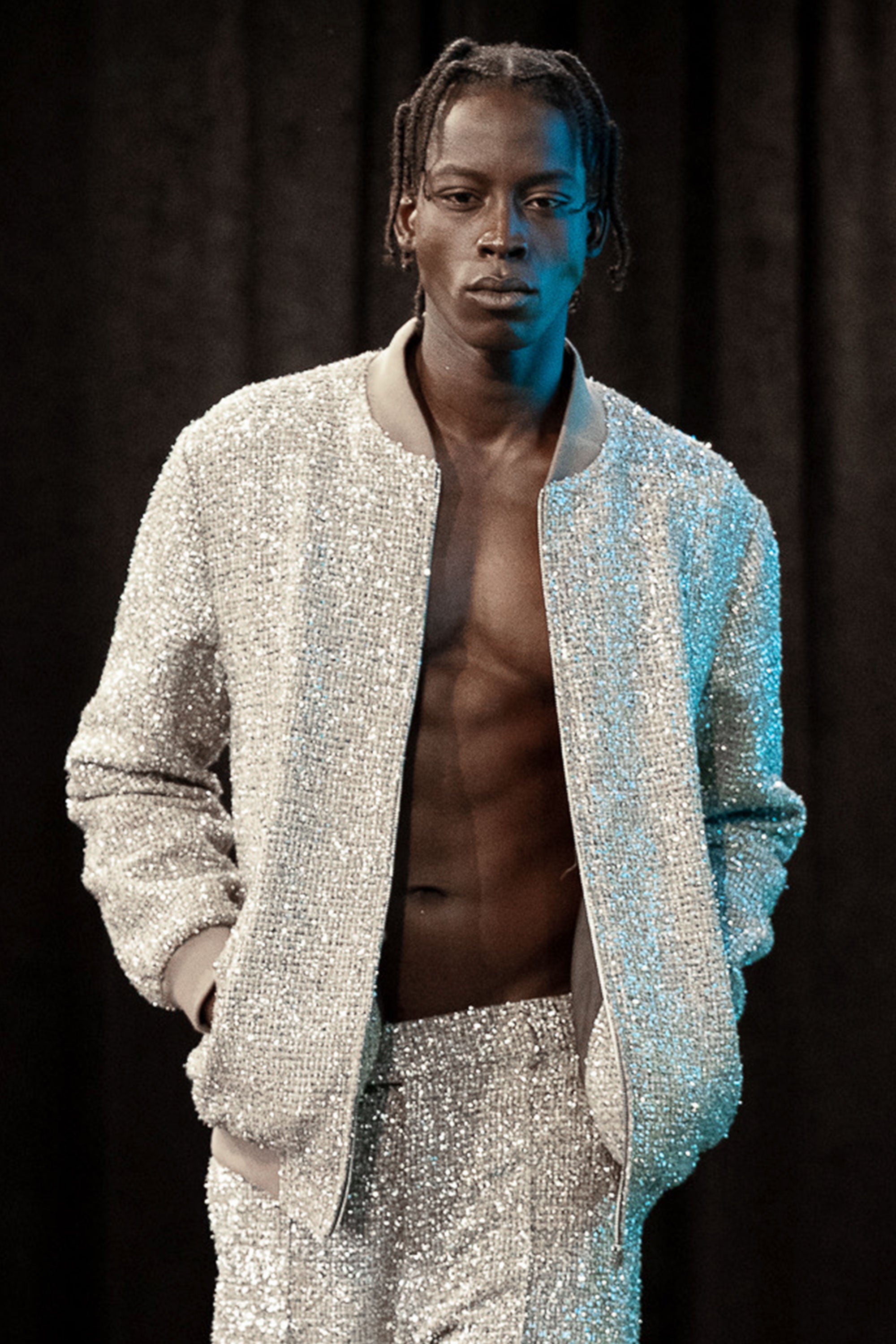 Person wearing a metallic tweed outfit against a dark background