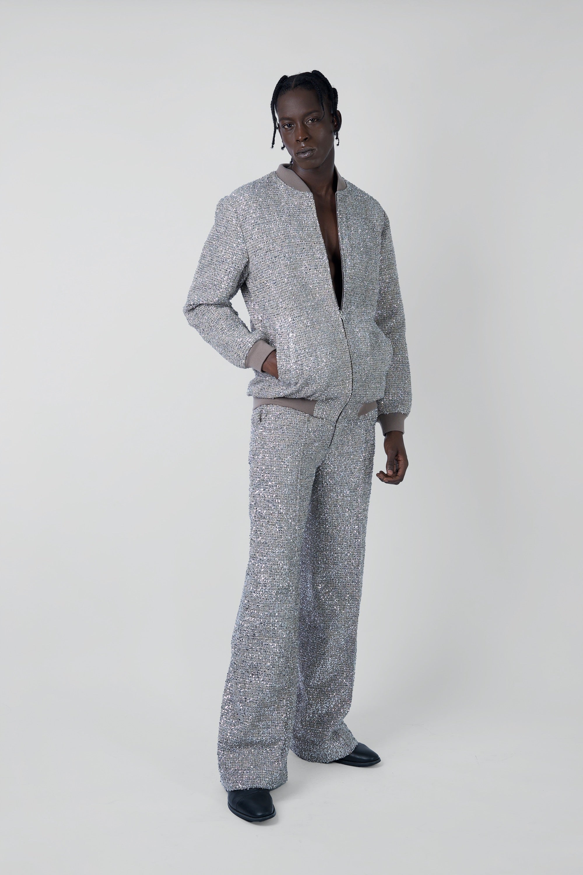 Person wearing a gray textured metallic tweed outfit on a white background